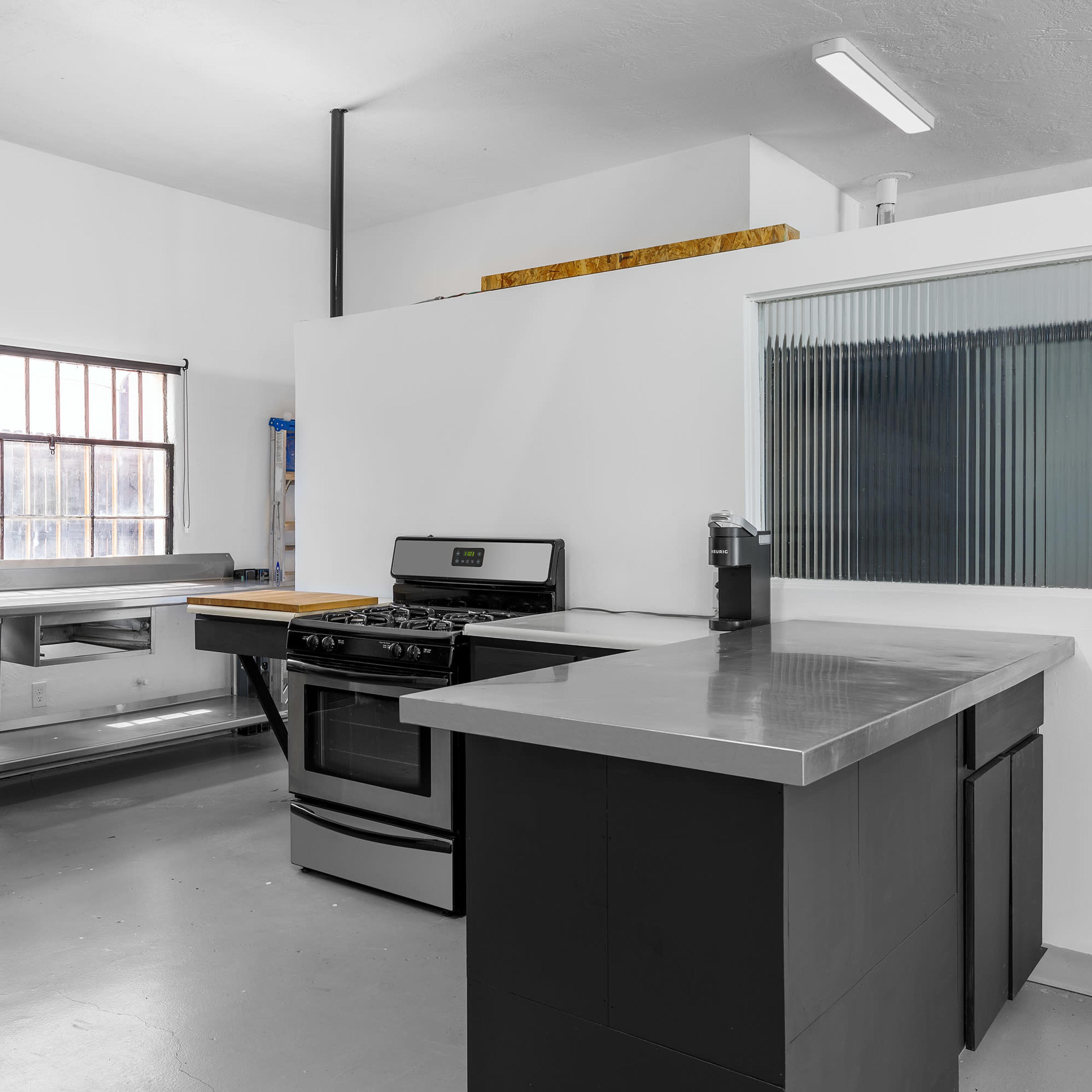 A modern kitchen with a stainless steel sink, a gas stove, and a minimalistic island countertop.