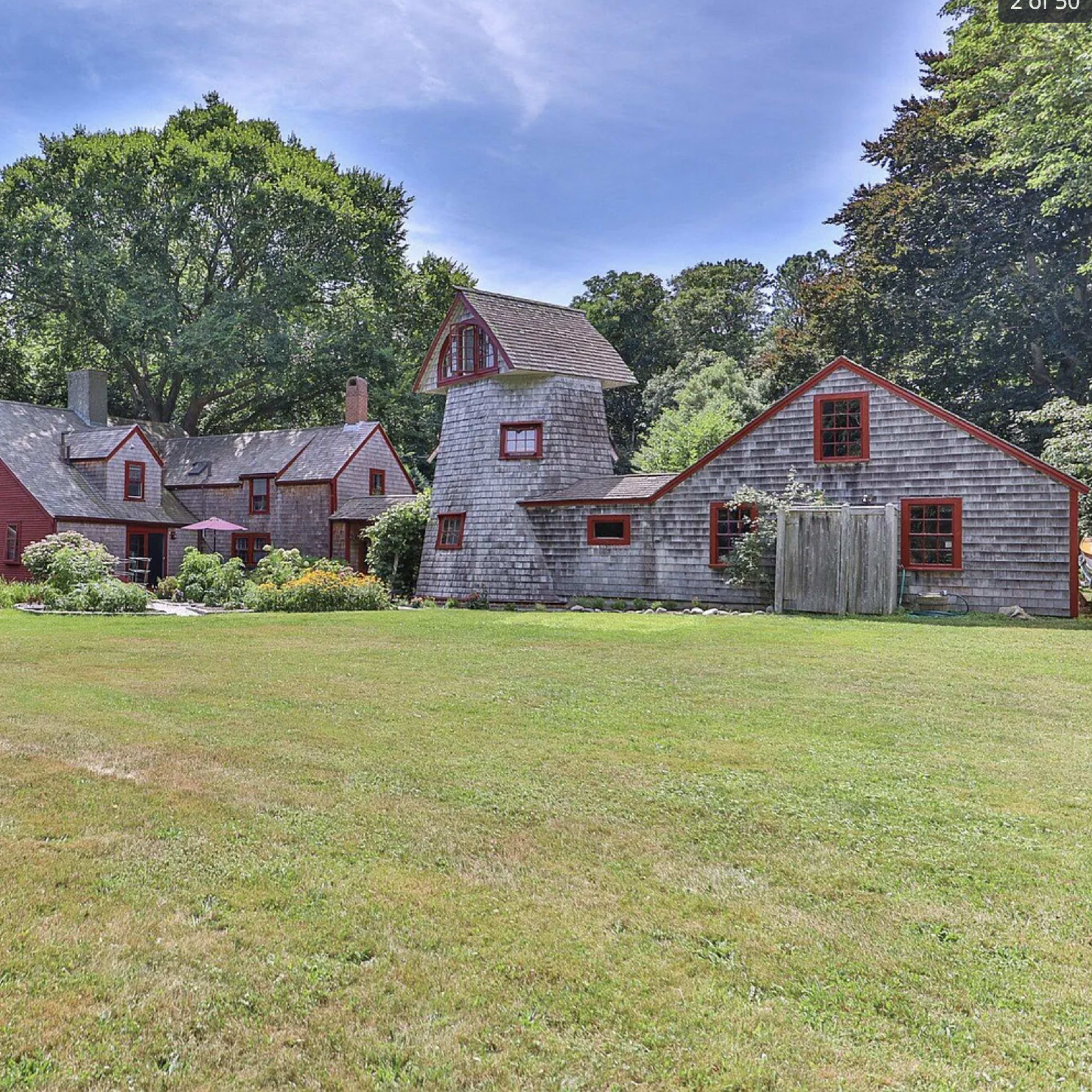 A large, multi-structure property featuring a red main house, a barn-like building, and a well-maintained yard with green grass and trees.