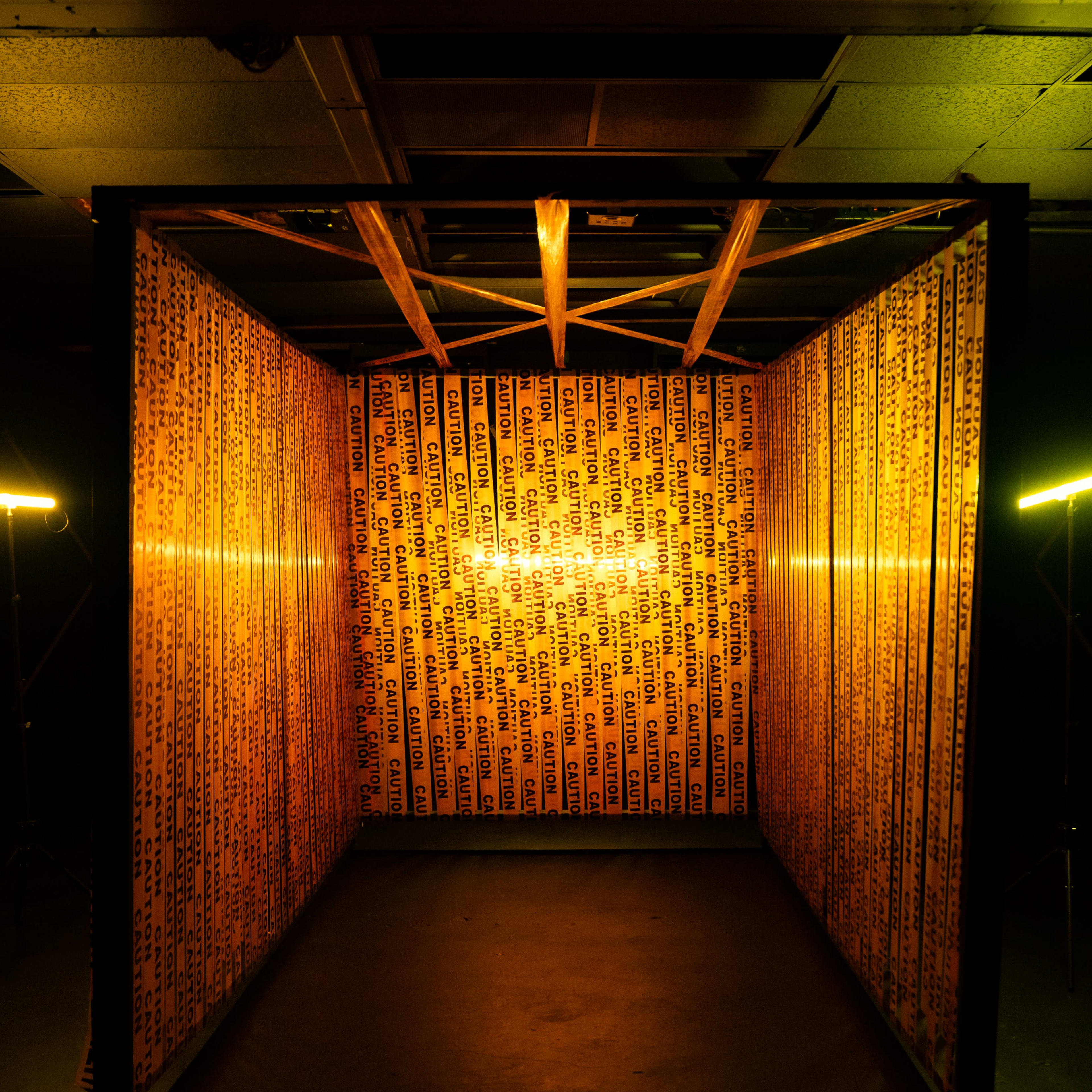 A small room is illuminated with warm yellow lighting and lined with patterned text on the walls.