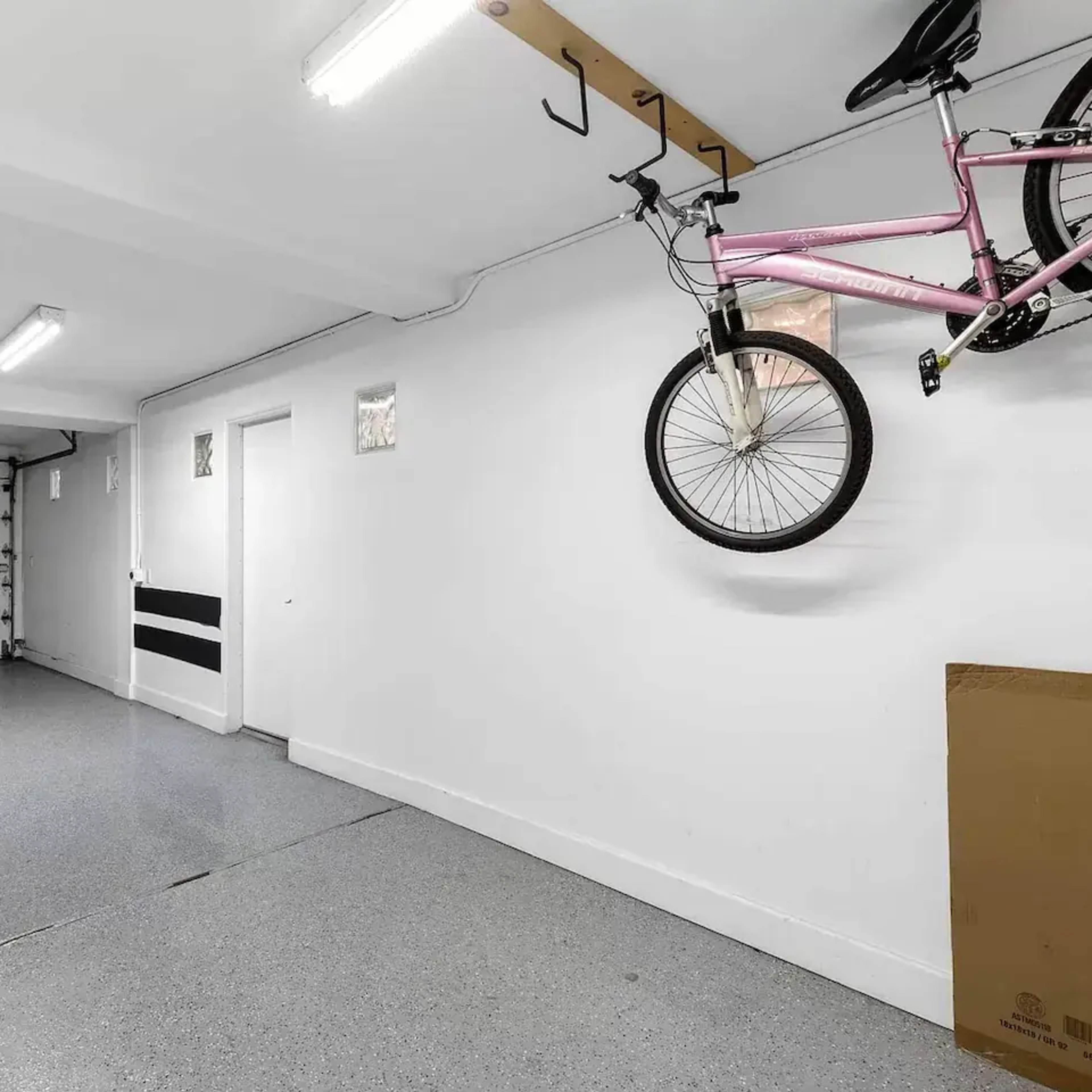 A spacious garage with a pink bicycle mounted on the wall and a large, empty floor area.