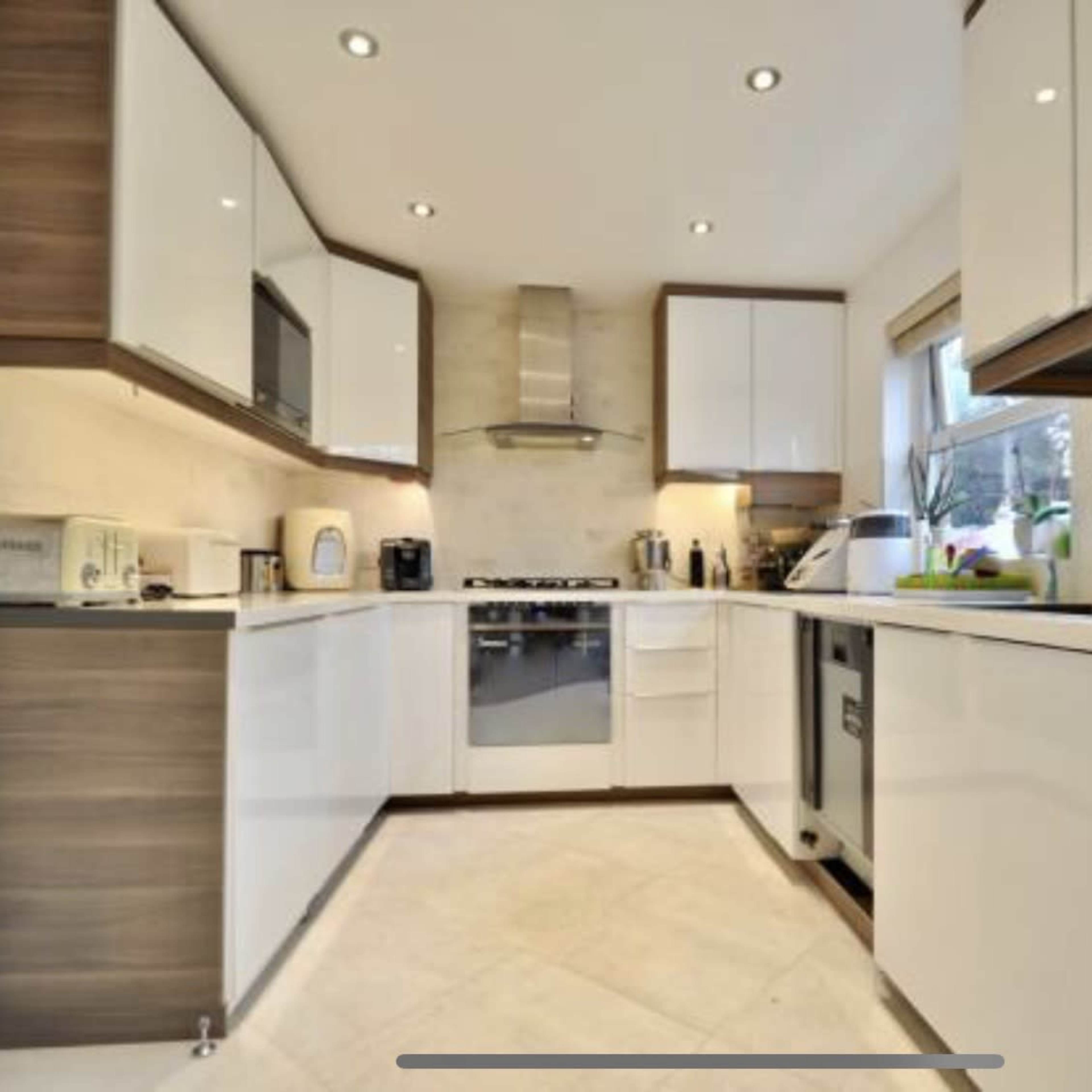The kitchen features modern cabinetry, stainless steel appliances, and a minimalist layout with white and wood finishes.