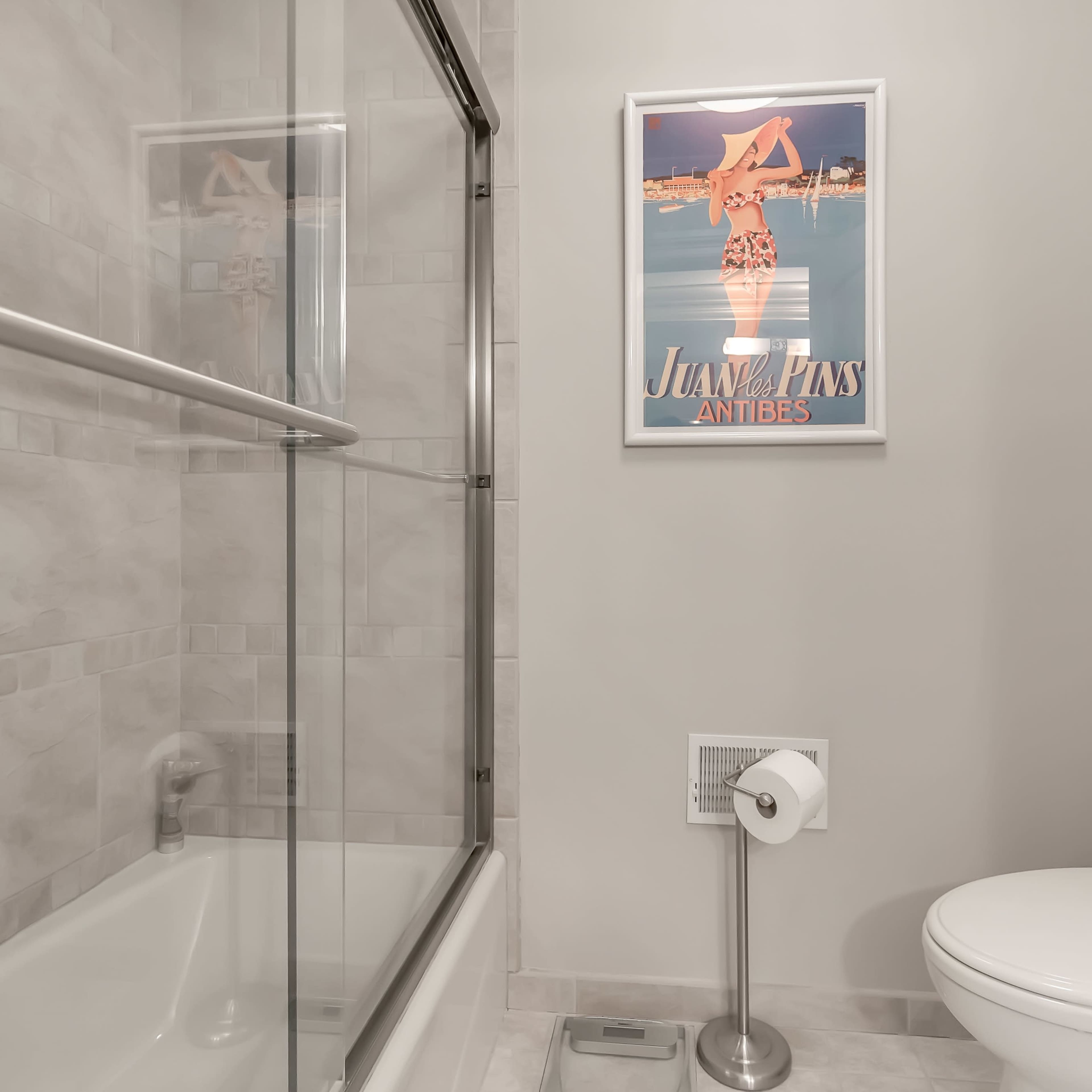 A bathroom featuring a walk-in shower with a glass door, a toilet, and a framed poster on the wall.