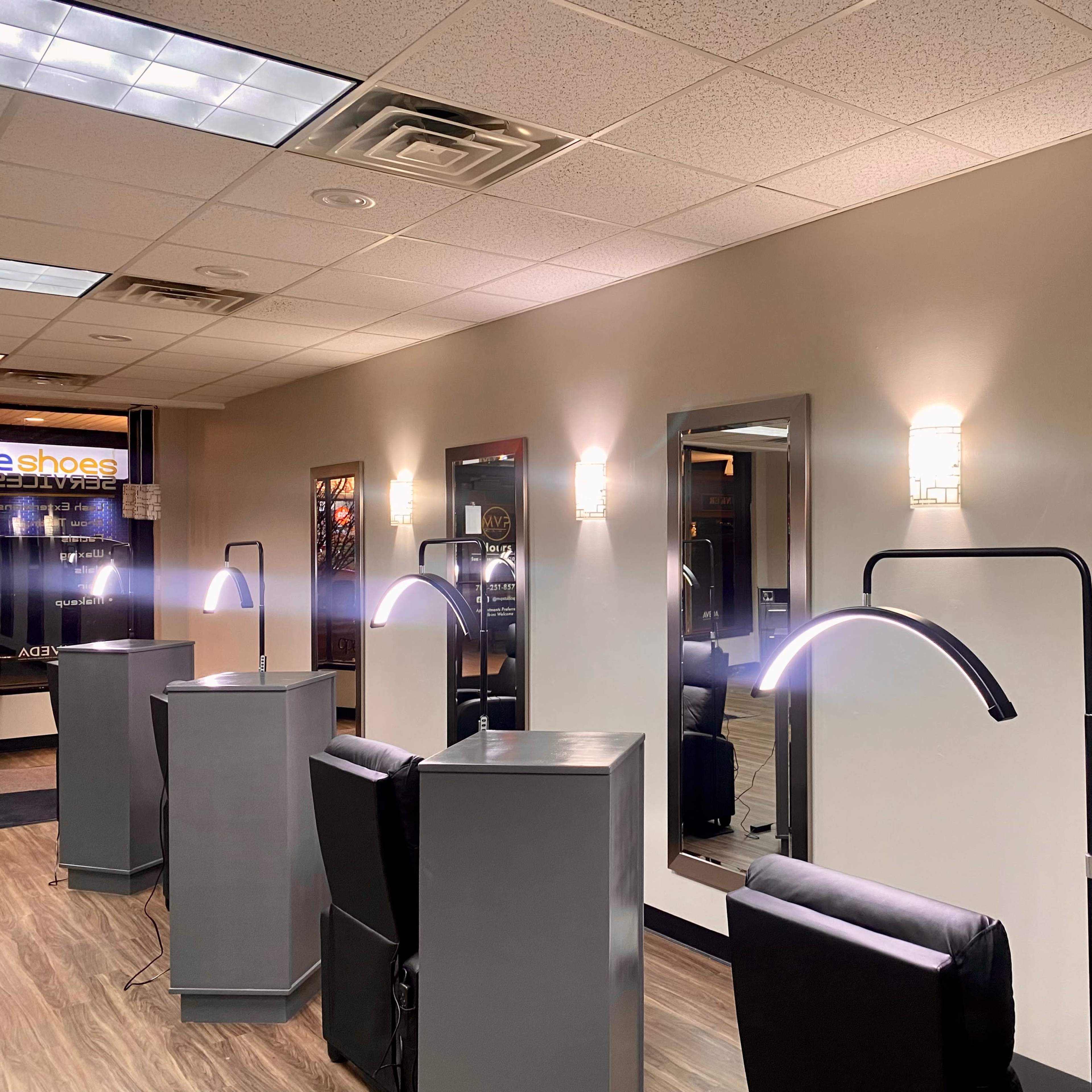 A modern salon interior with several illuminated mirrors and styling stations arranged along the walls.