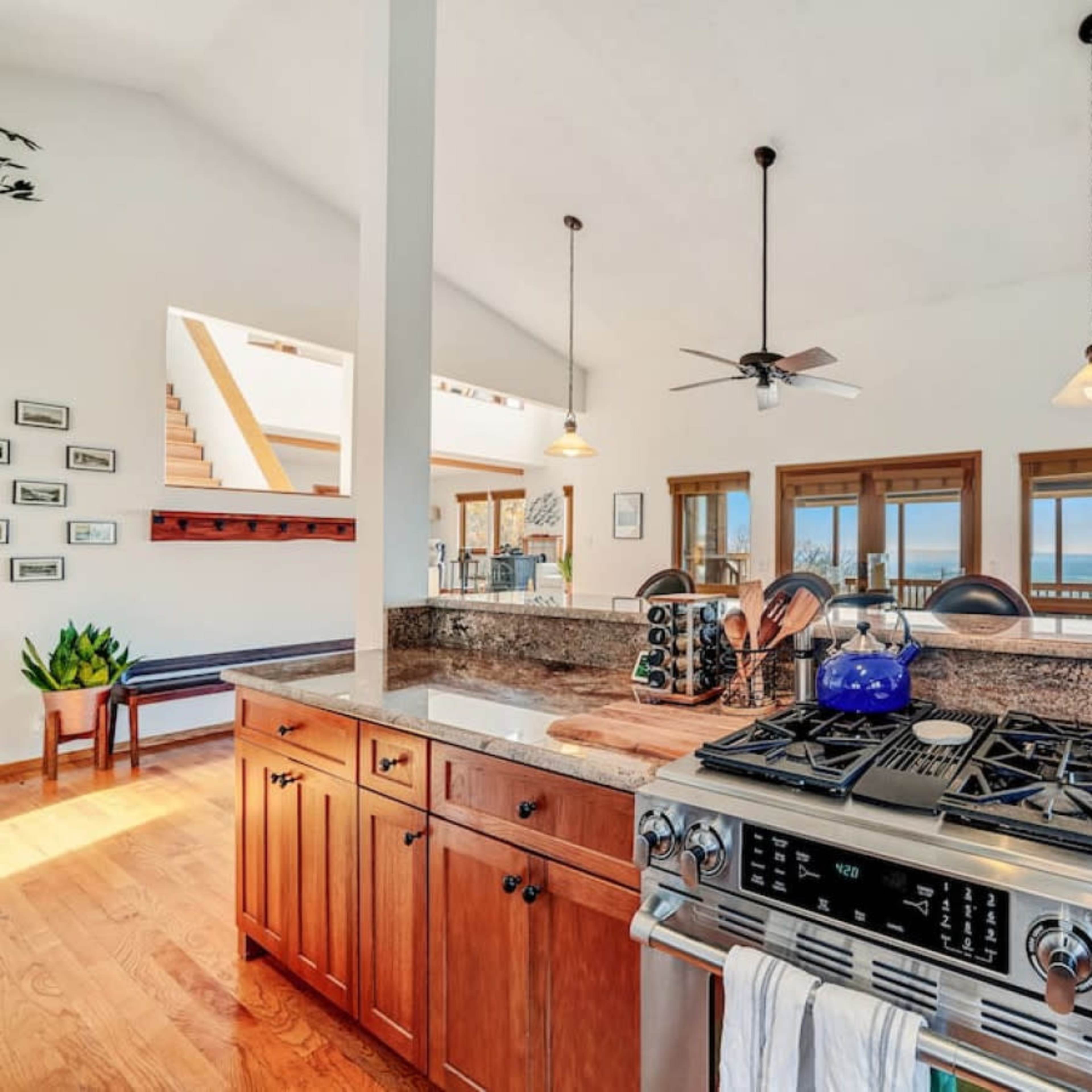 A modern kitchen with a large island, granite countertops, and a scenic view through the windows.