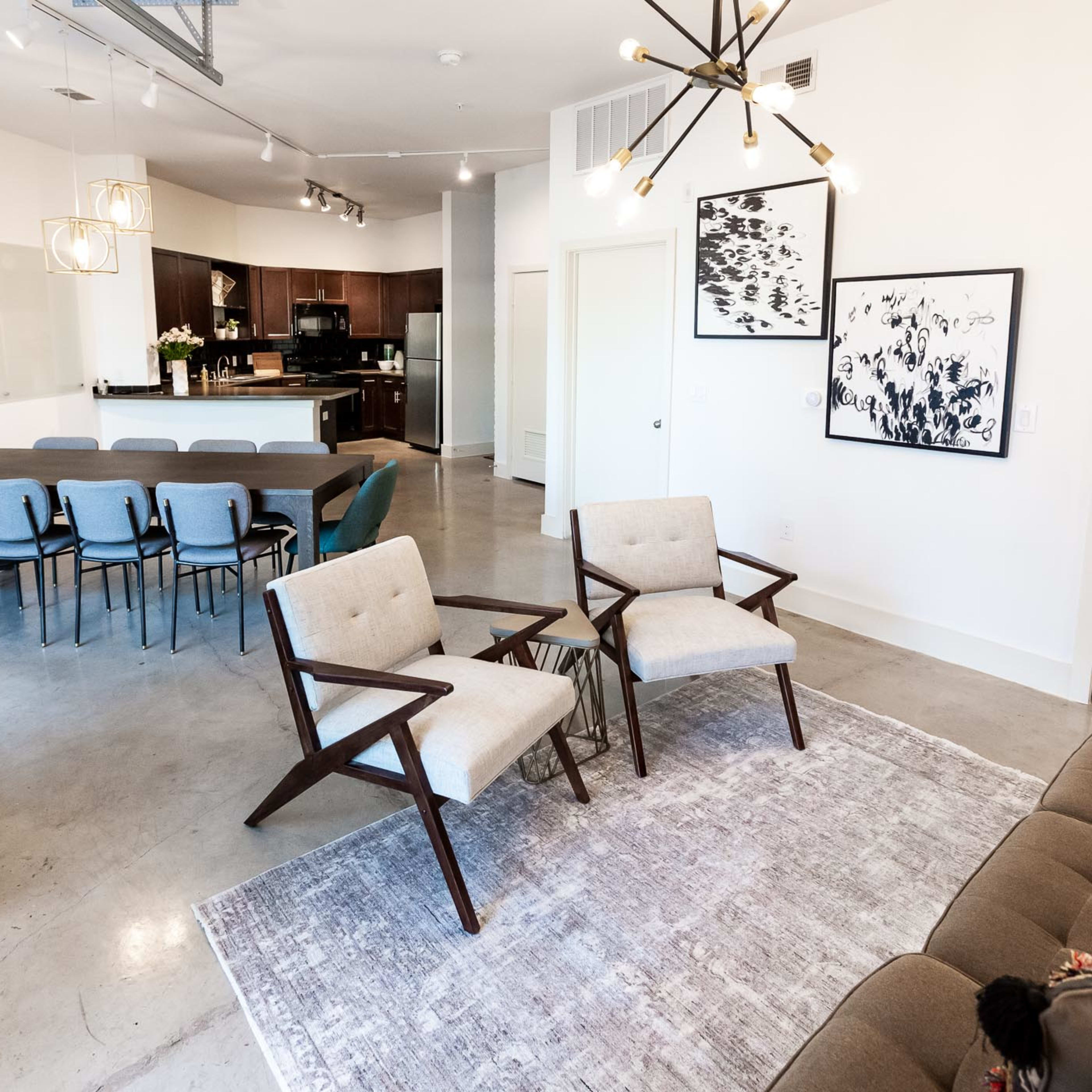 A modern, open-concept interior with a dining table, kitchen area, and seating arrangements including two chairs and a sofa.