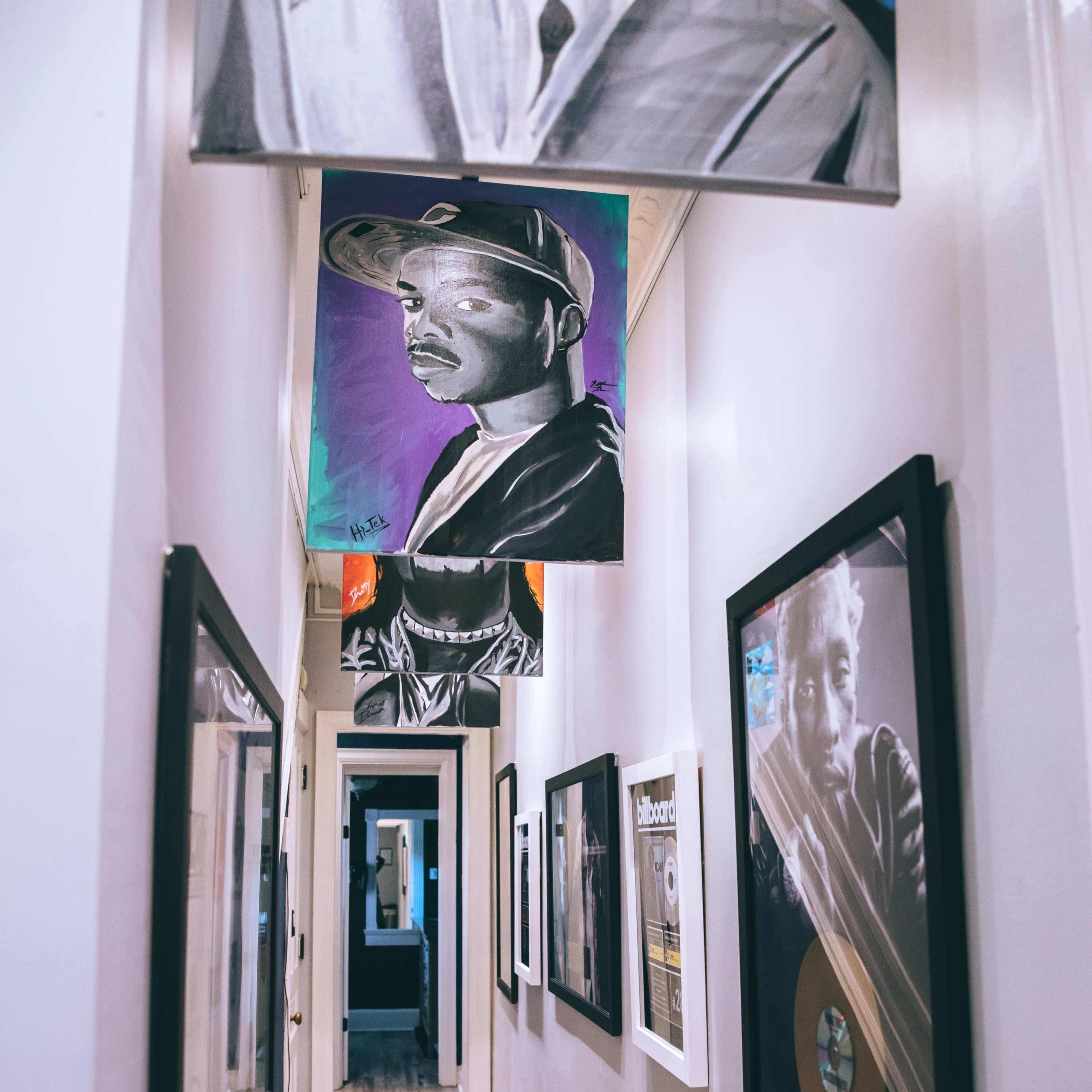 A narrow hallway lined with framed photographs and artwork, leading to an open space at the far end.
