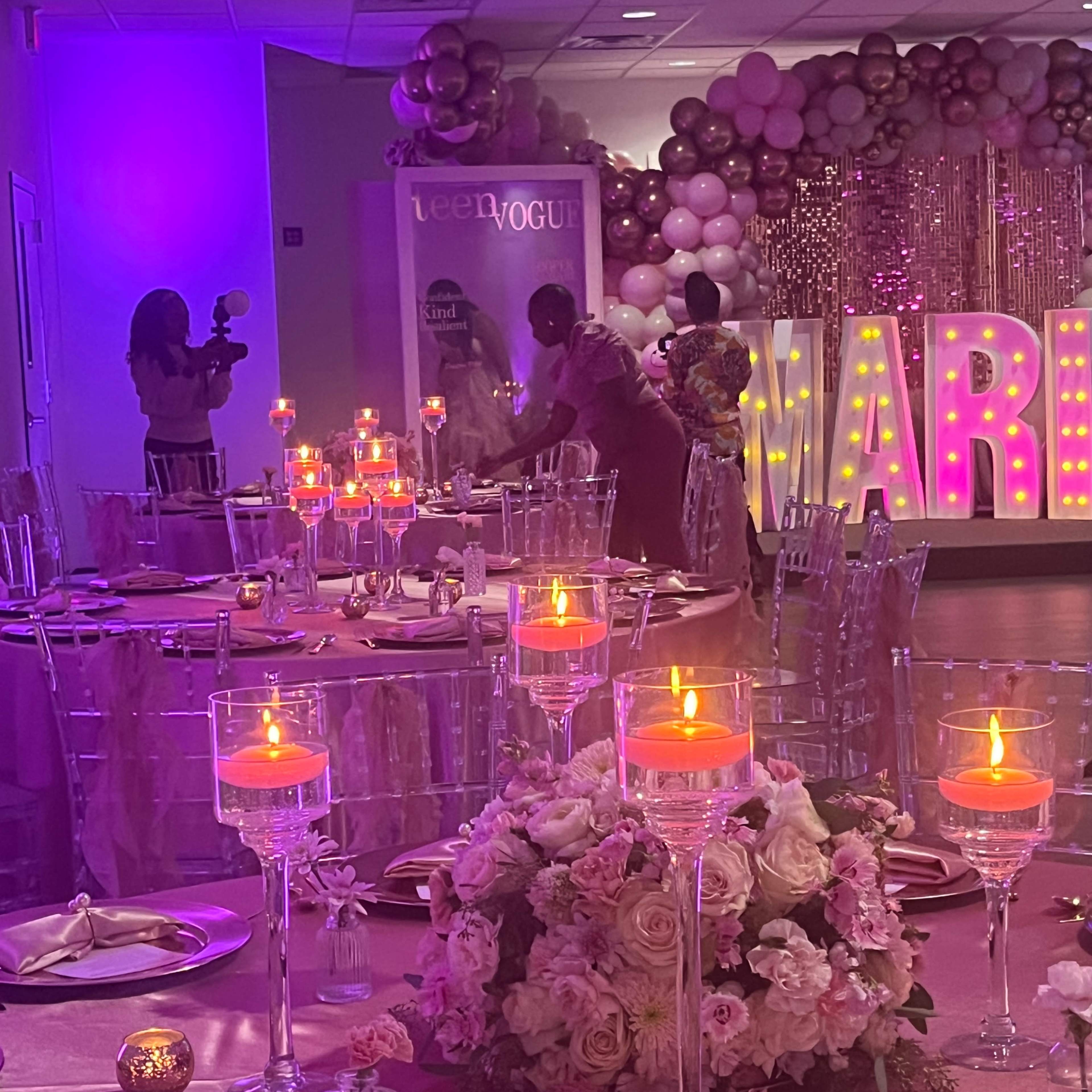 A decorated banquet hall features tables set with candles and floral arrangements, while large illuminated letters spell "MARRIED" in the background.