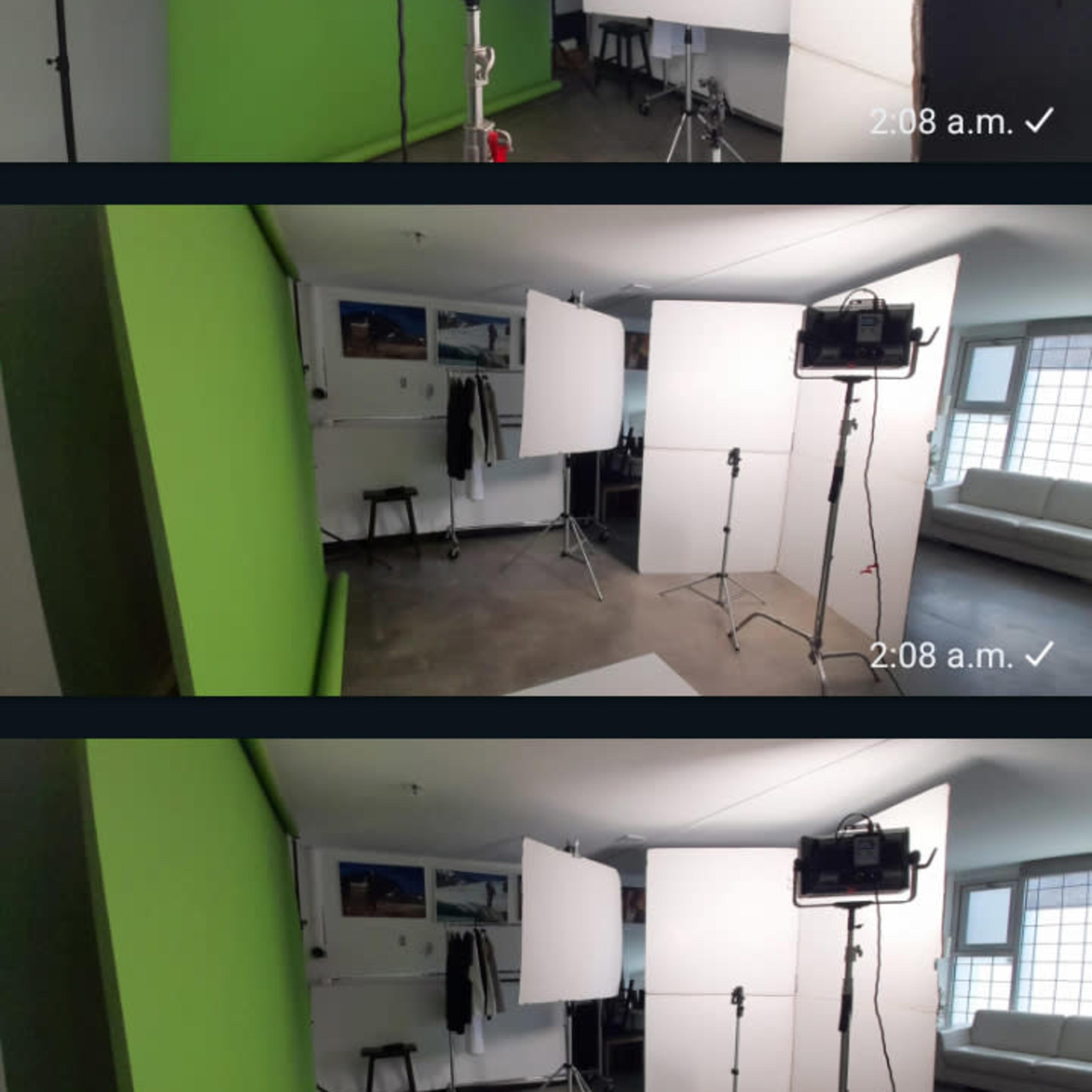 A photography studio with various backdrops, lighting equipment, and light stands set up in a well-lit room.