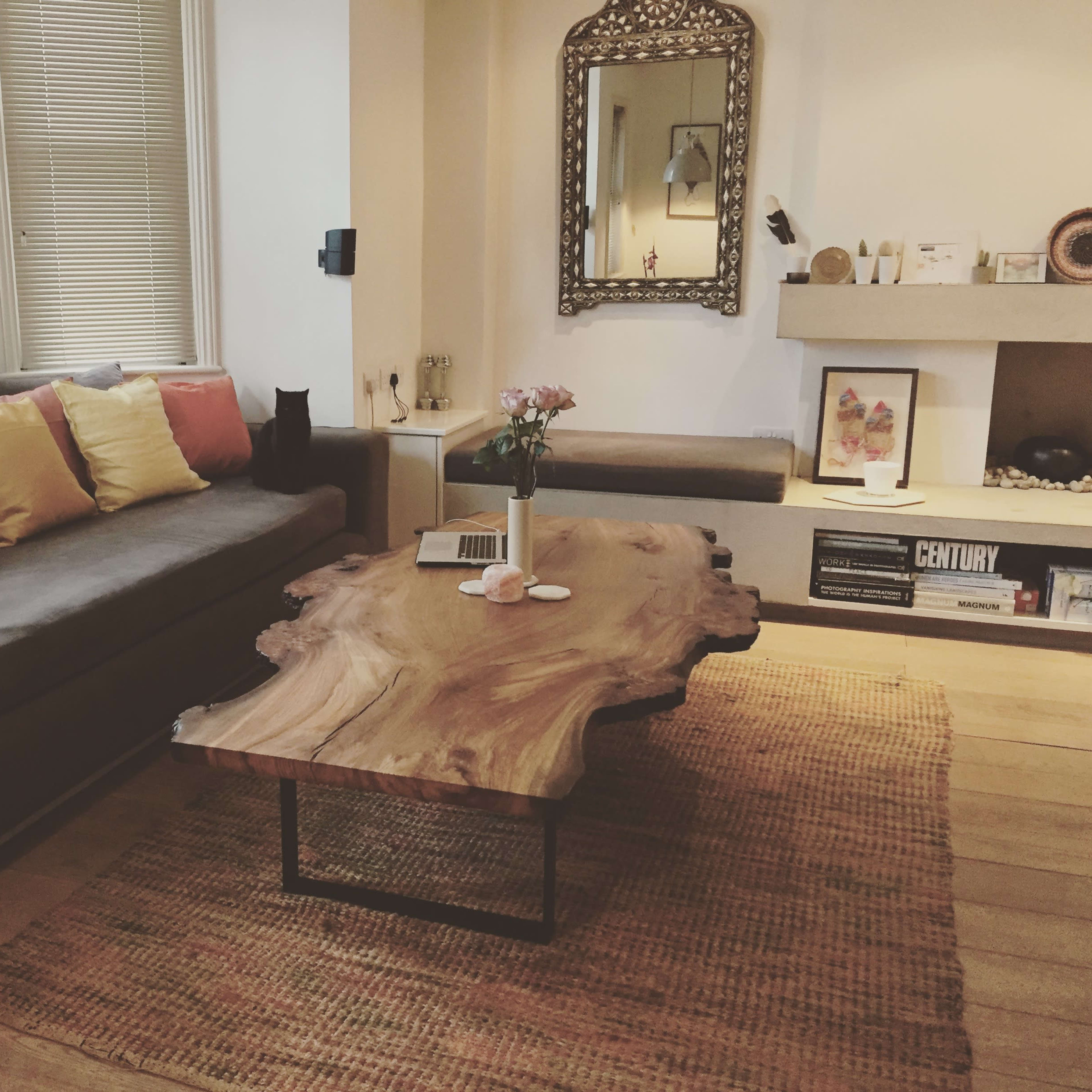 A living room with a gray sofa adorned with colorful pillows, a wooden coffee table, and a rug on the wooden floor.
