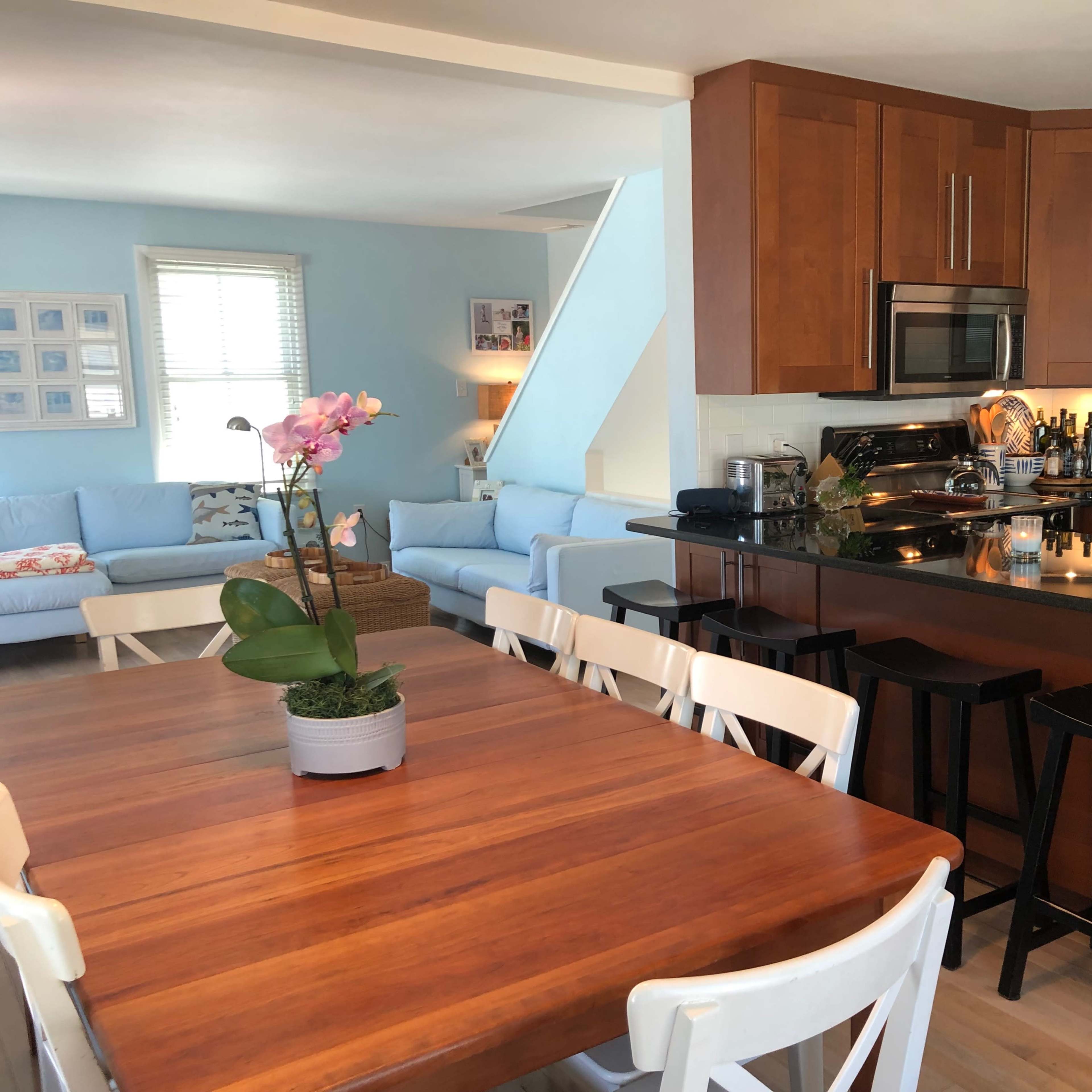 A modern kitchen with brown cabinetry and a dining area featuring a wooden table and white chairs.
