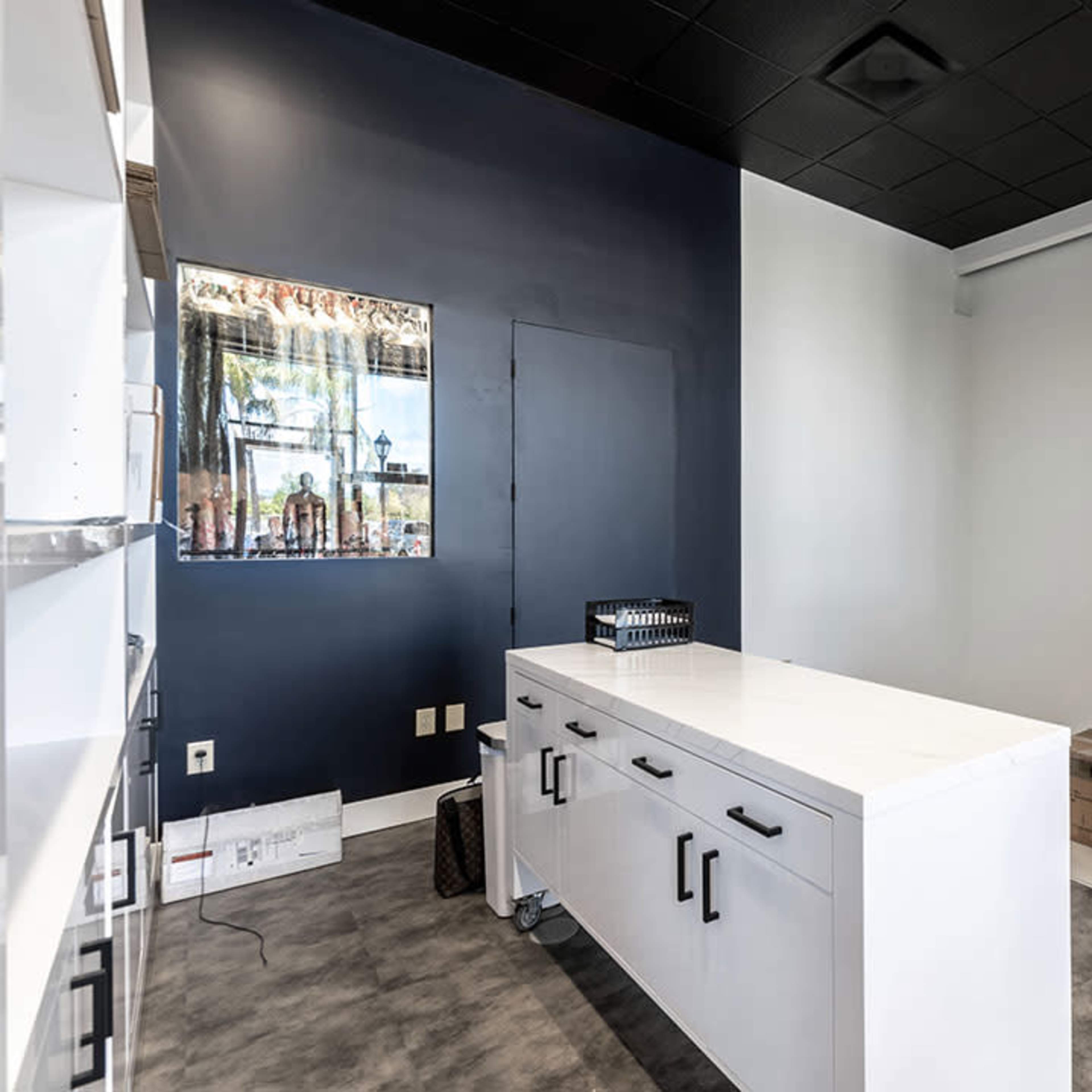 A modern retail space with a sleek check-out counter, display shelves on the right, and a mirrored wall with a TV mounted above.