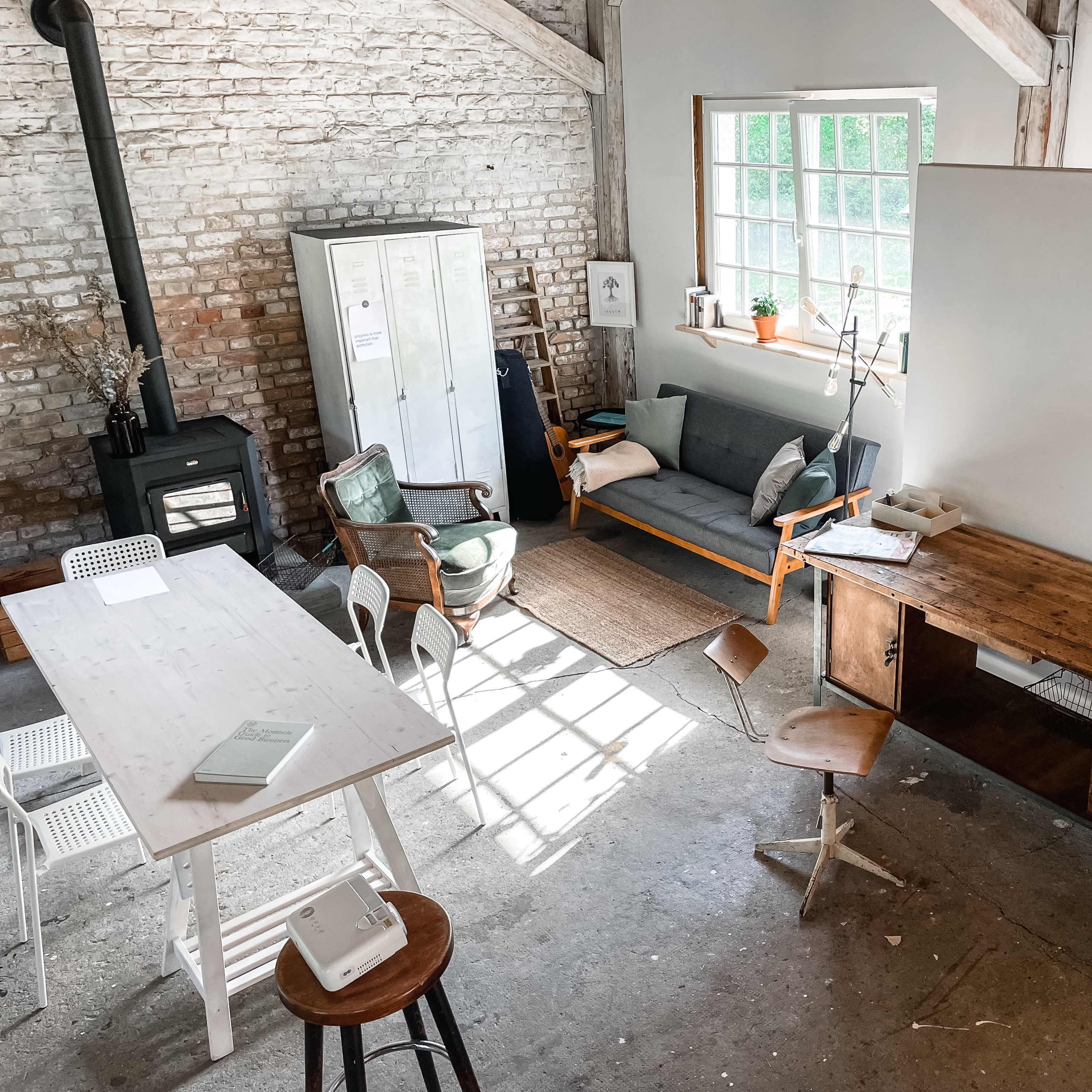 A spacious, minimalist office with a wooden desk, chairs, and a large window letting in natural light.