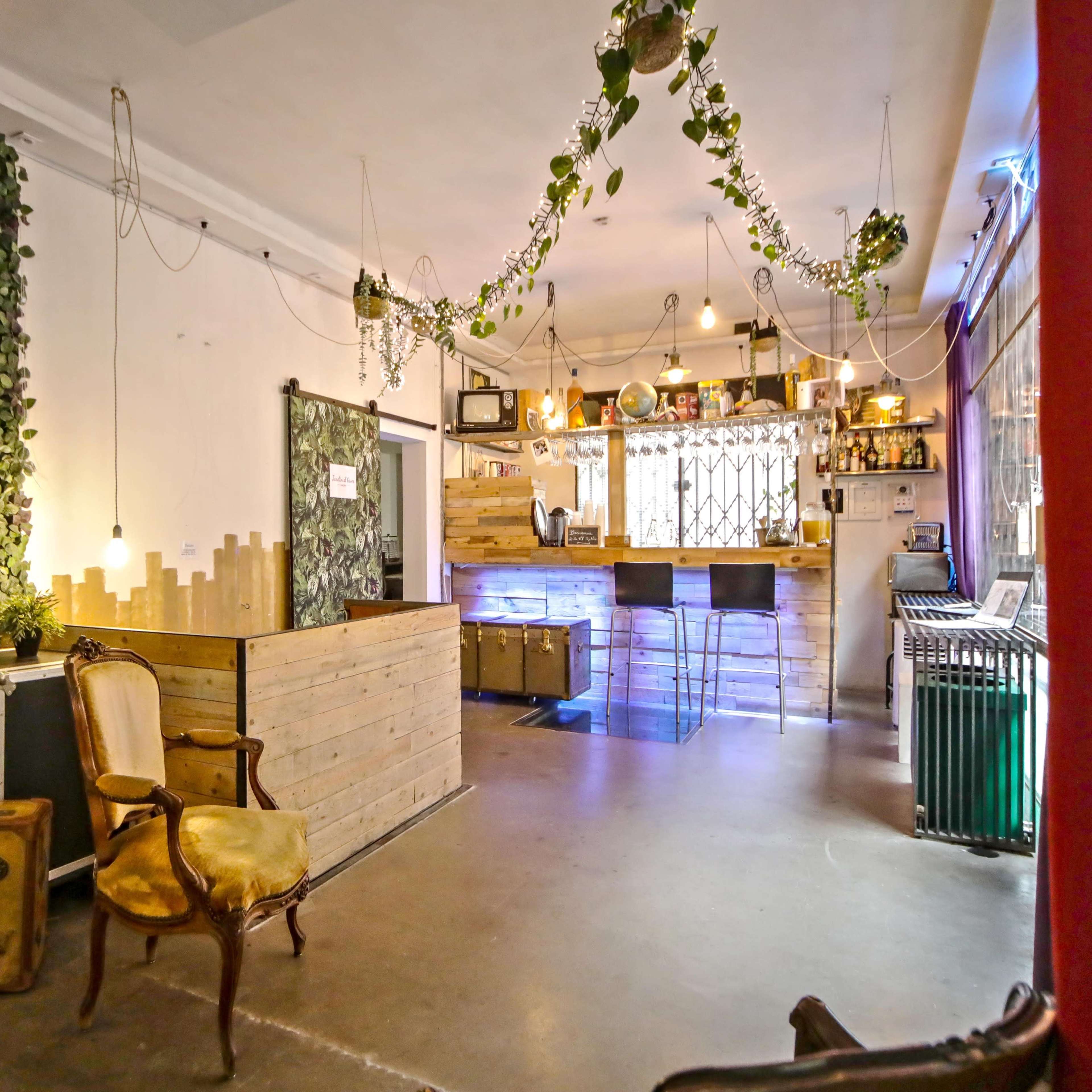 An interior space with a bar area, wooden counter, and greenery on the walls, illuminated by pendant lights.