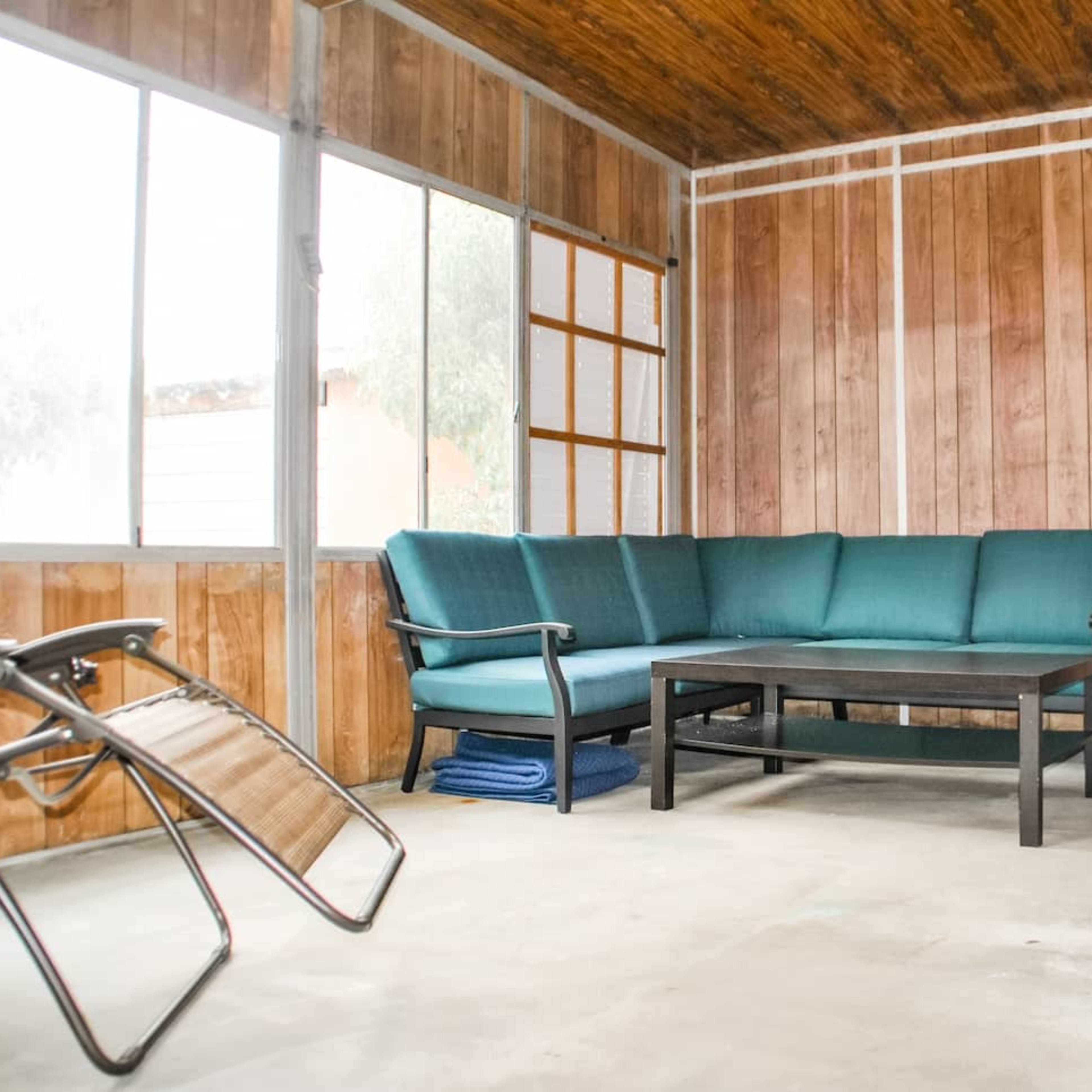 A simple indoor seating area with a green couch, a black coffee table, and wooden walls.