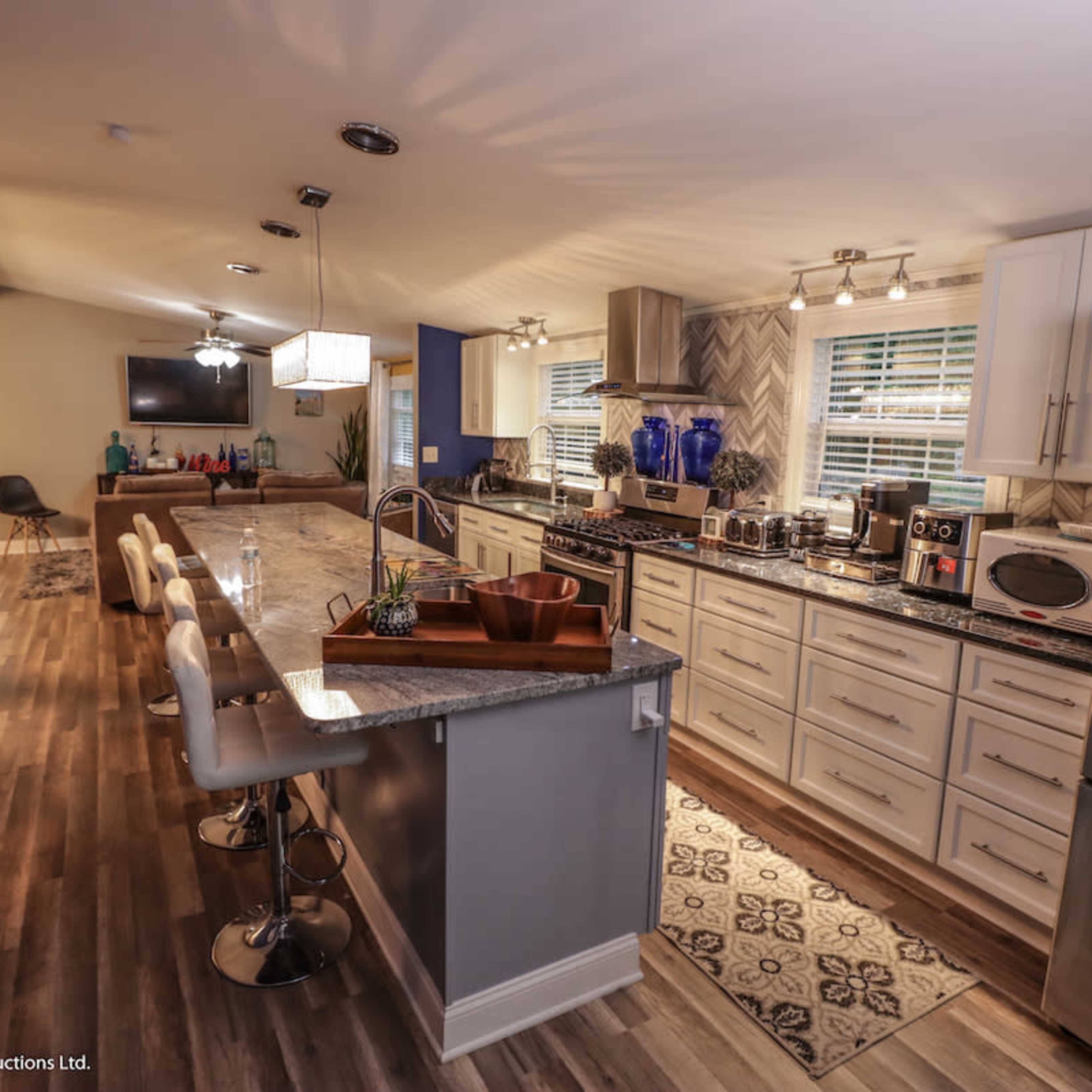 A modern kitchen features an island with bar seating, stainless steel appliances, and a combination of light and dark cabinetry.