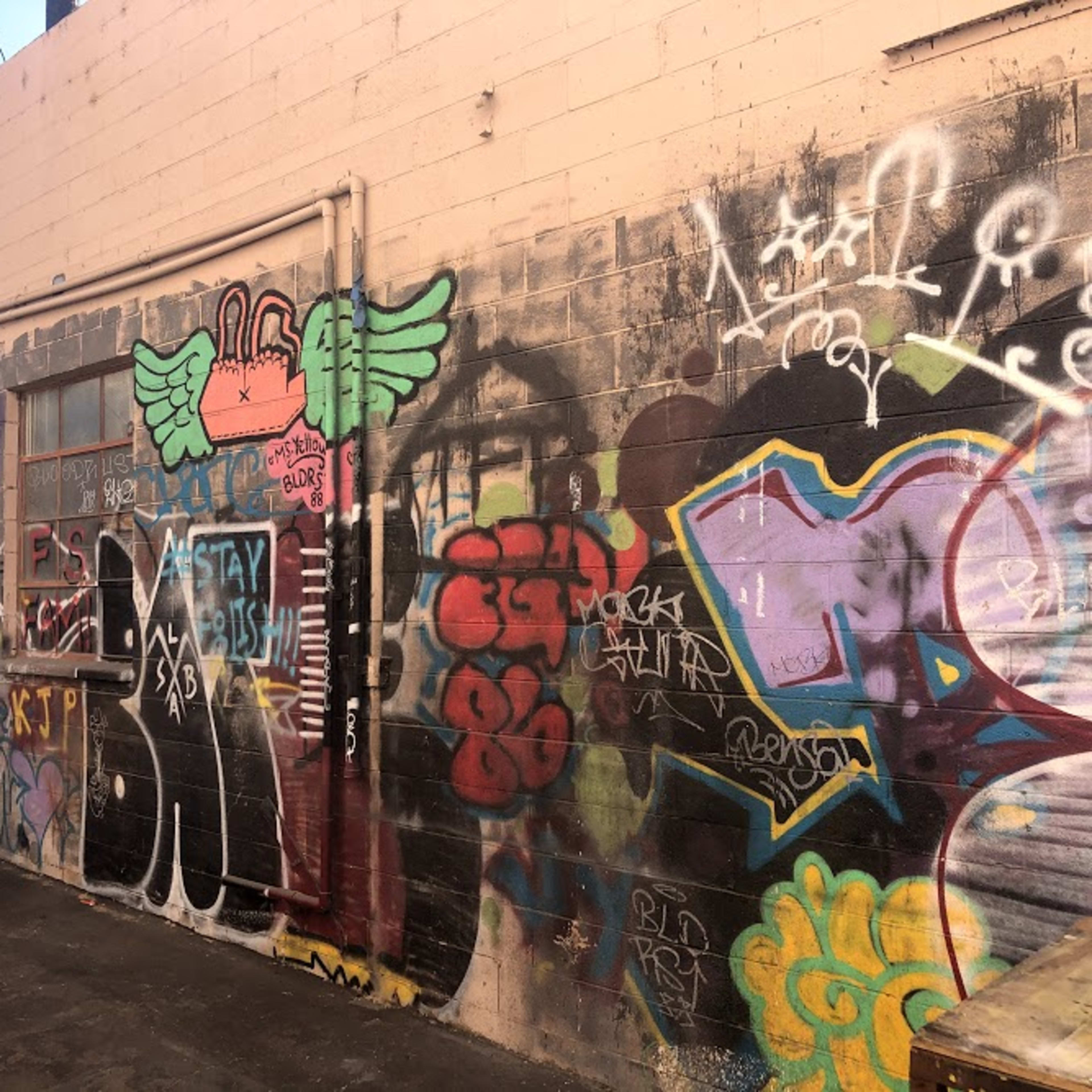 A wall covered in vibrant graffiti art, featuring various colorful designs and tags.