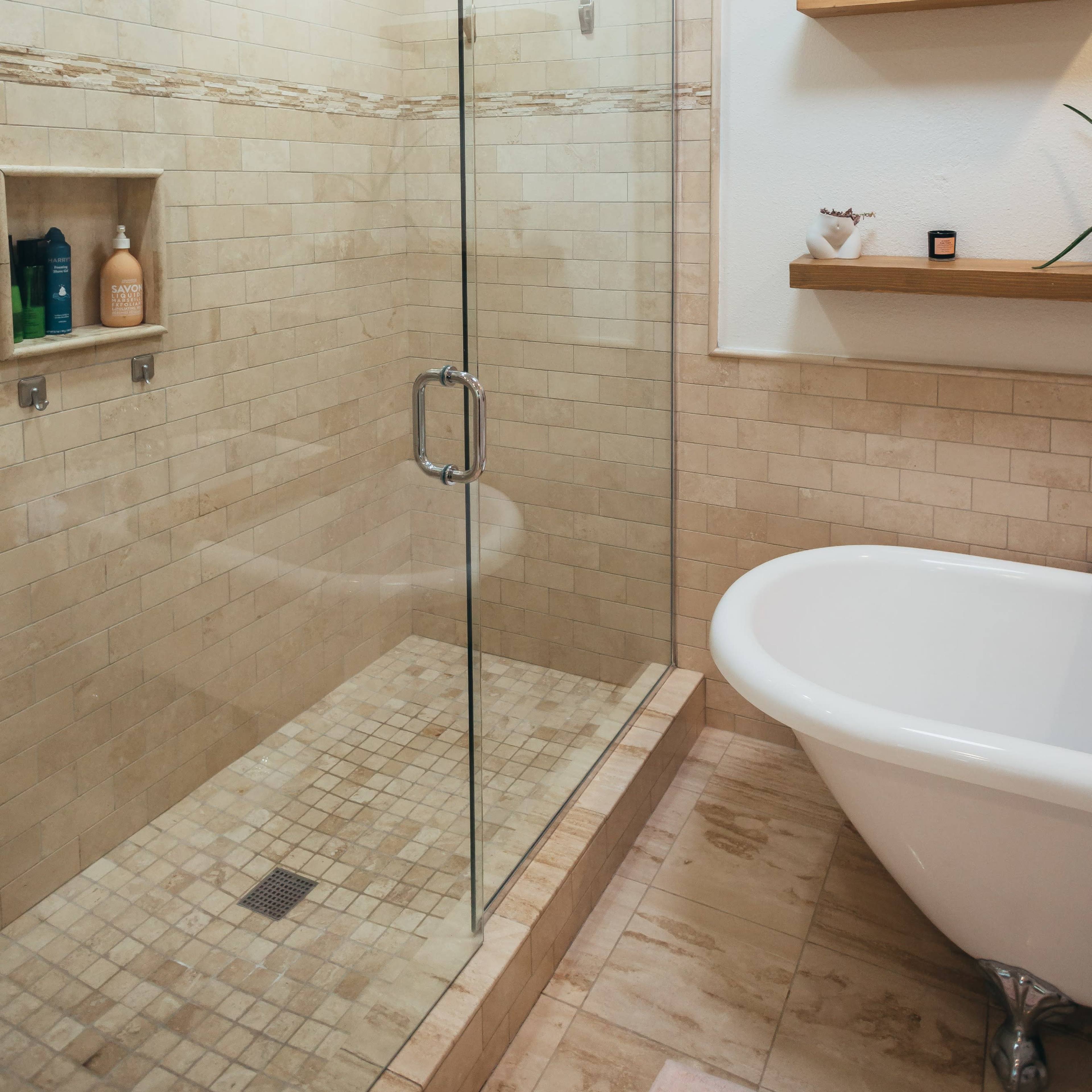 A modern bathroom with a glass shower enclosure, a freestanding bathtub, and tiled walls.