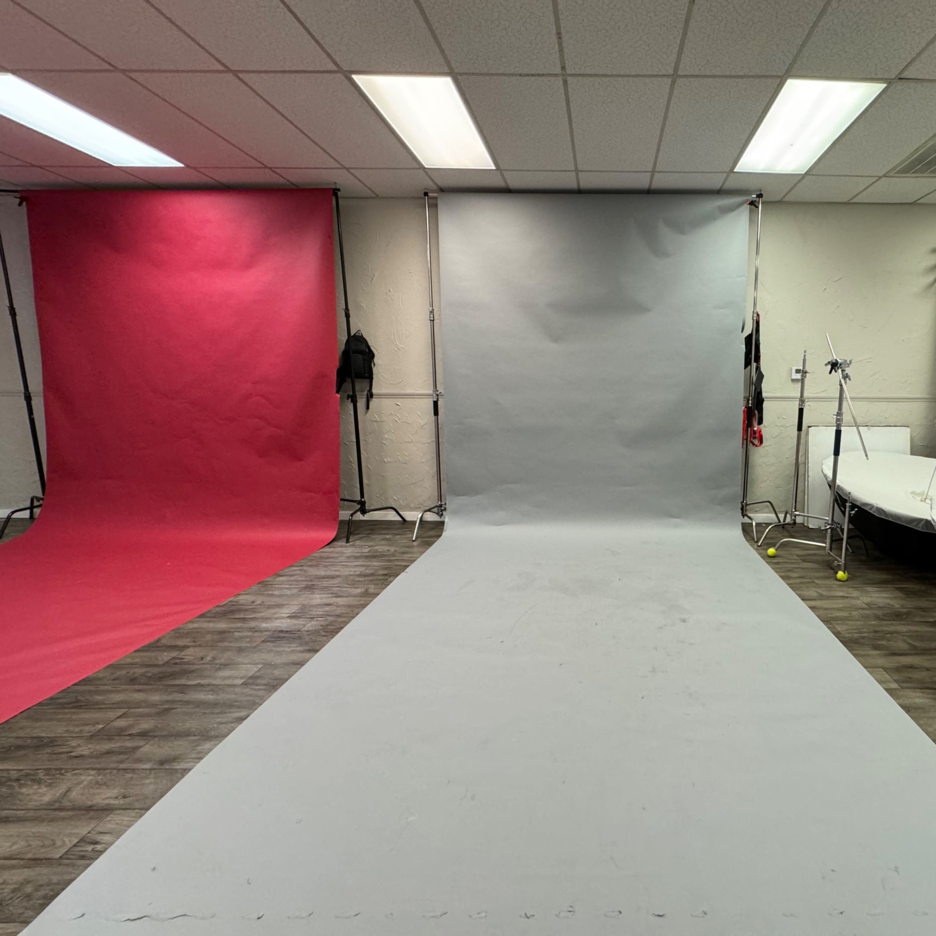 A photography studio with three colored backdrops, including red, grey, and brown, arranged around a central shooting area with a light setup.