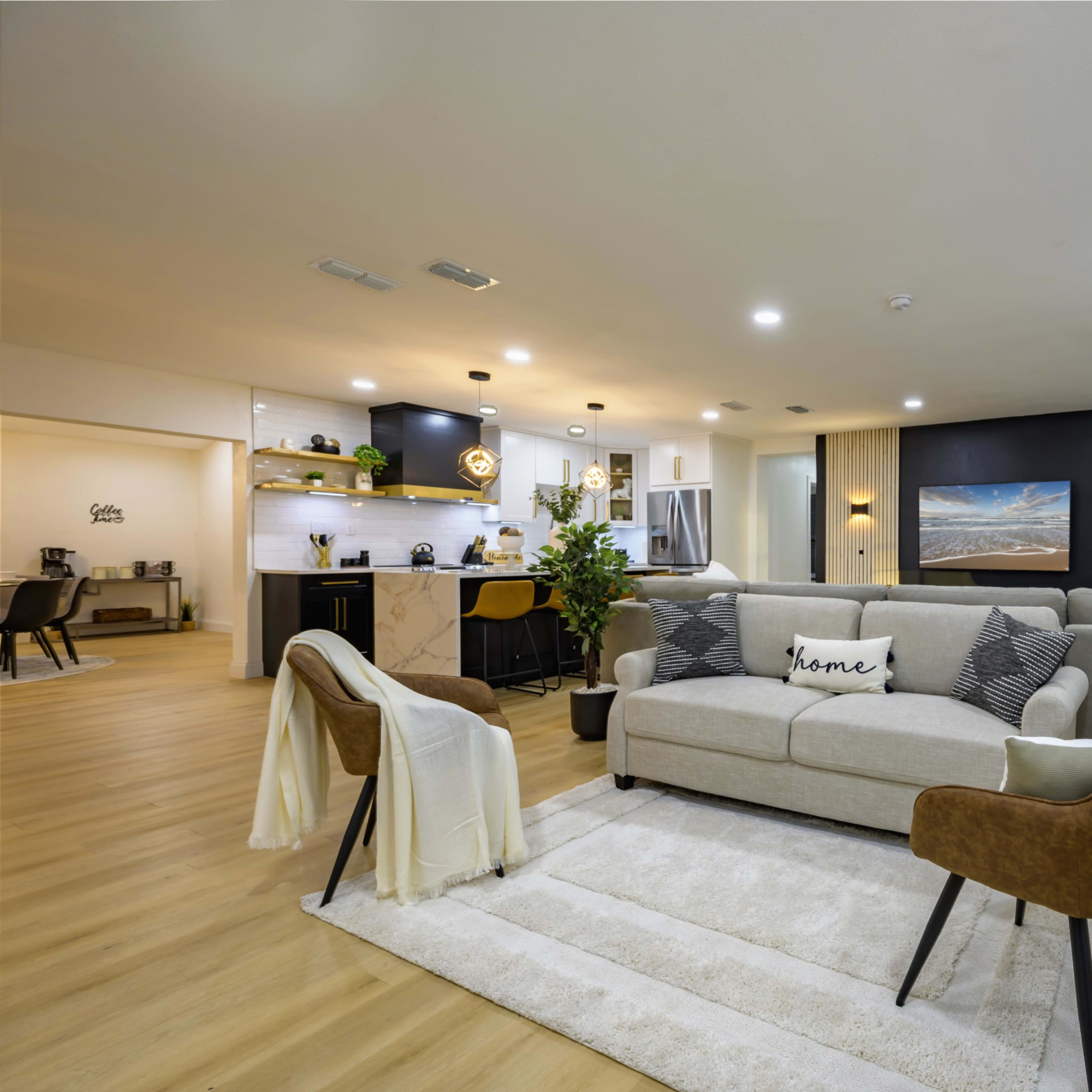 A modern living room with a light-colored sofa, two brown chairs, and a large window, all set against a mix of light and dark walls.