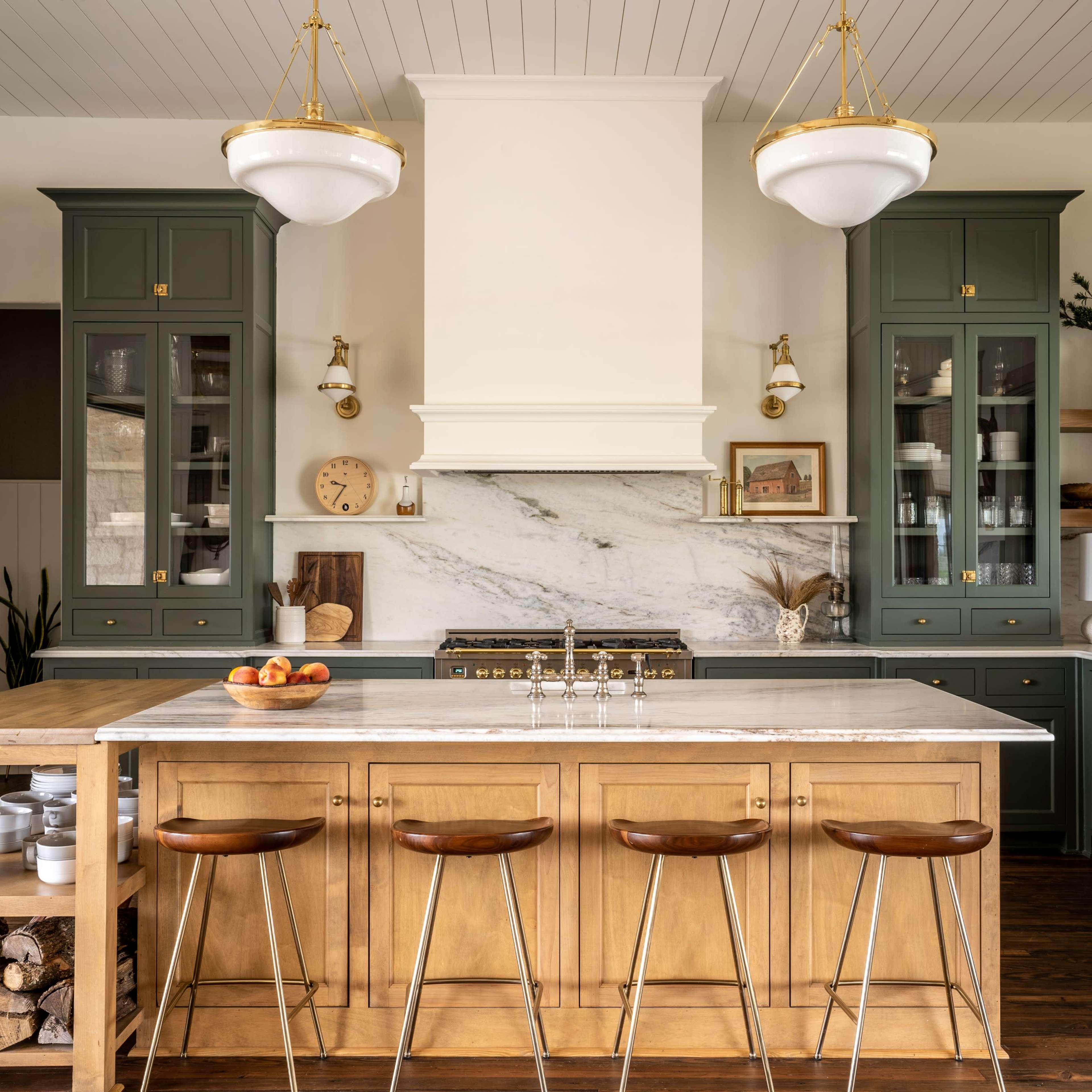 The kitchen features green cabinetry, a large central island with a marble countertop, and wooden bar stools.