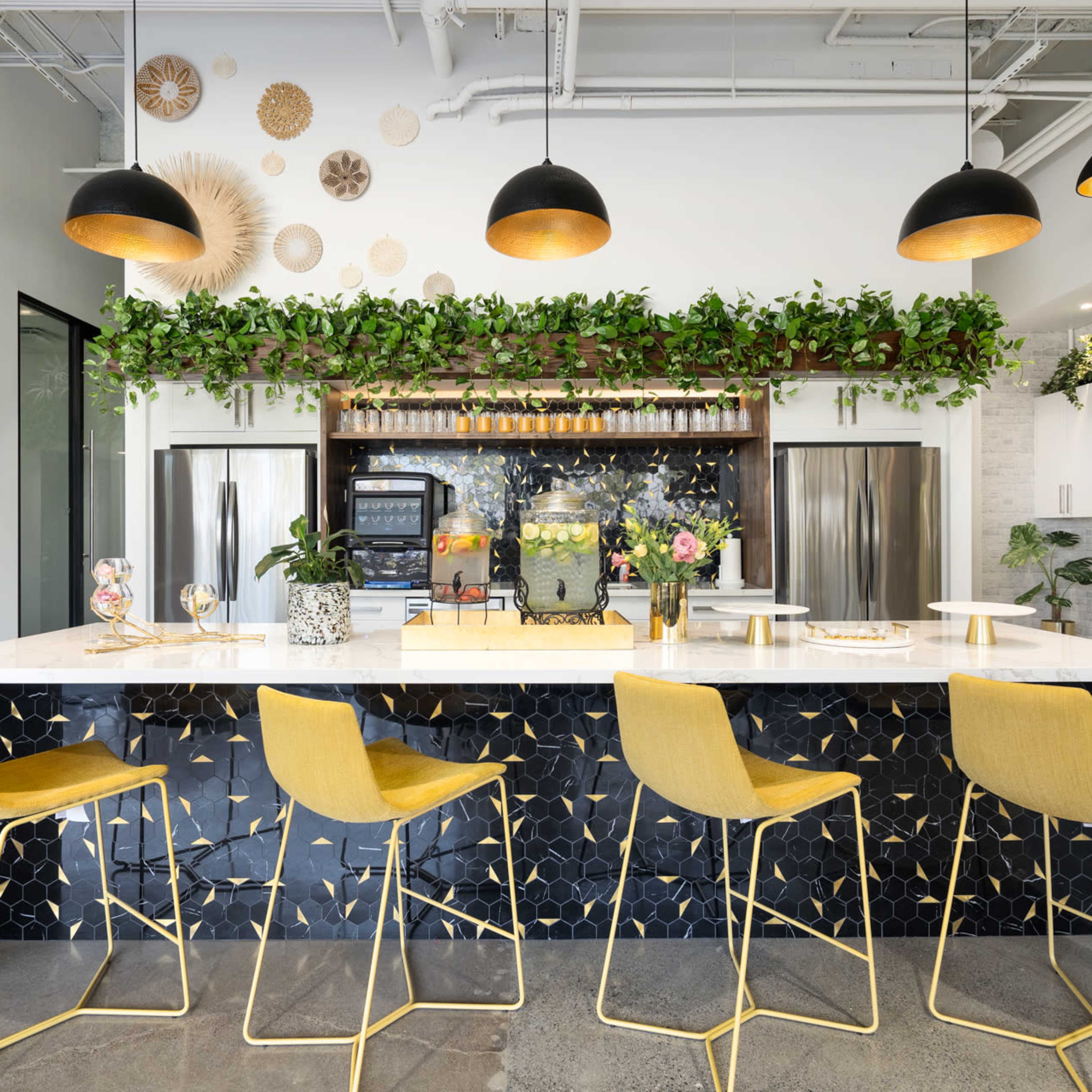 A modern office interior featuring a collaborative workspace with bright yellow and white accents, comfortable seating areas, and a large meeting room visible through glass walls.