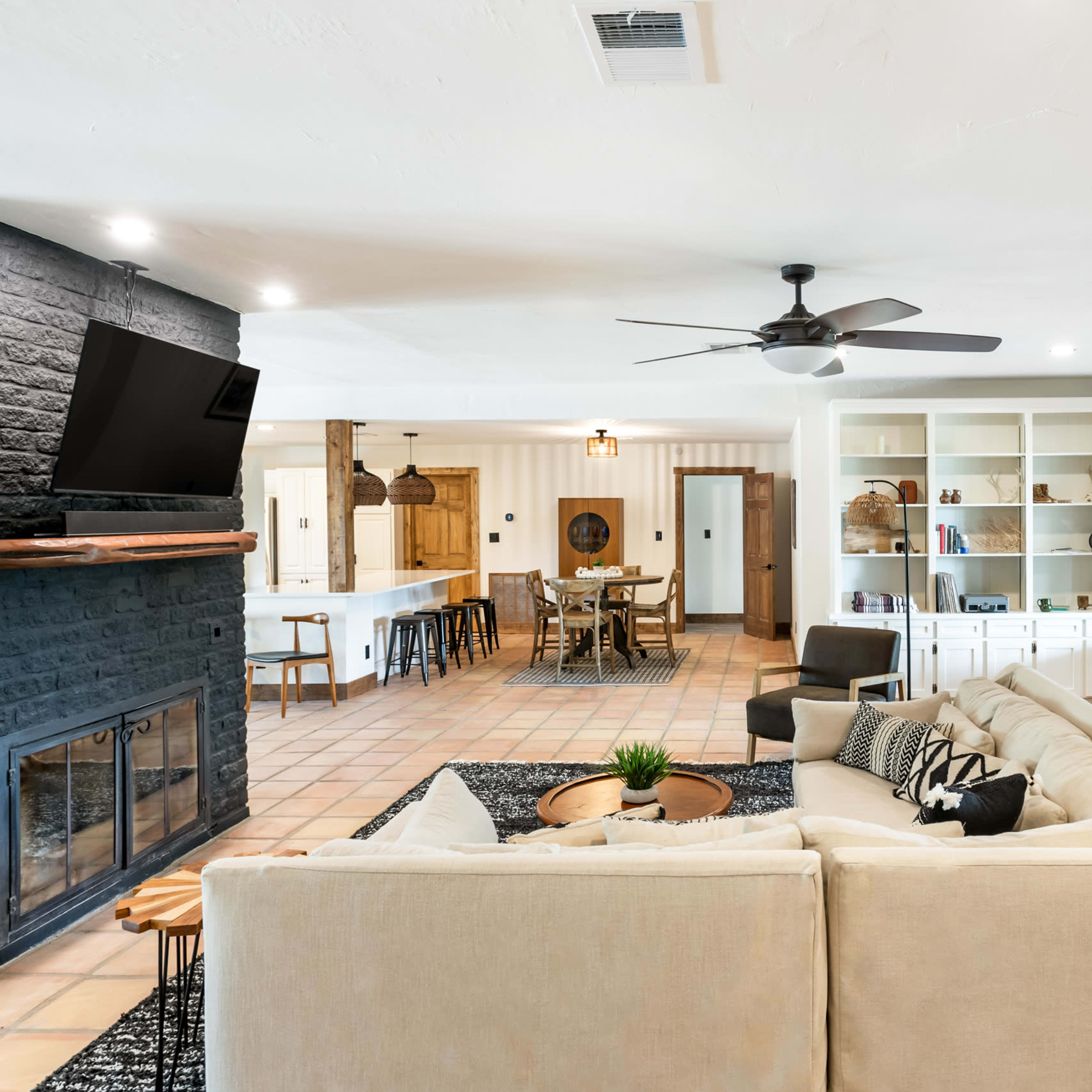 A spacious living room featuring a large sectional sofa, a fireplace, and an open layout leading to a dining area and kitchen.