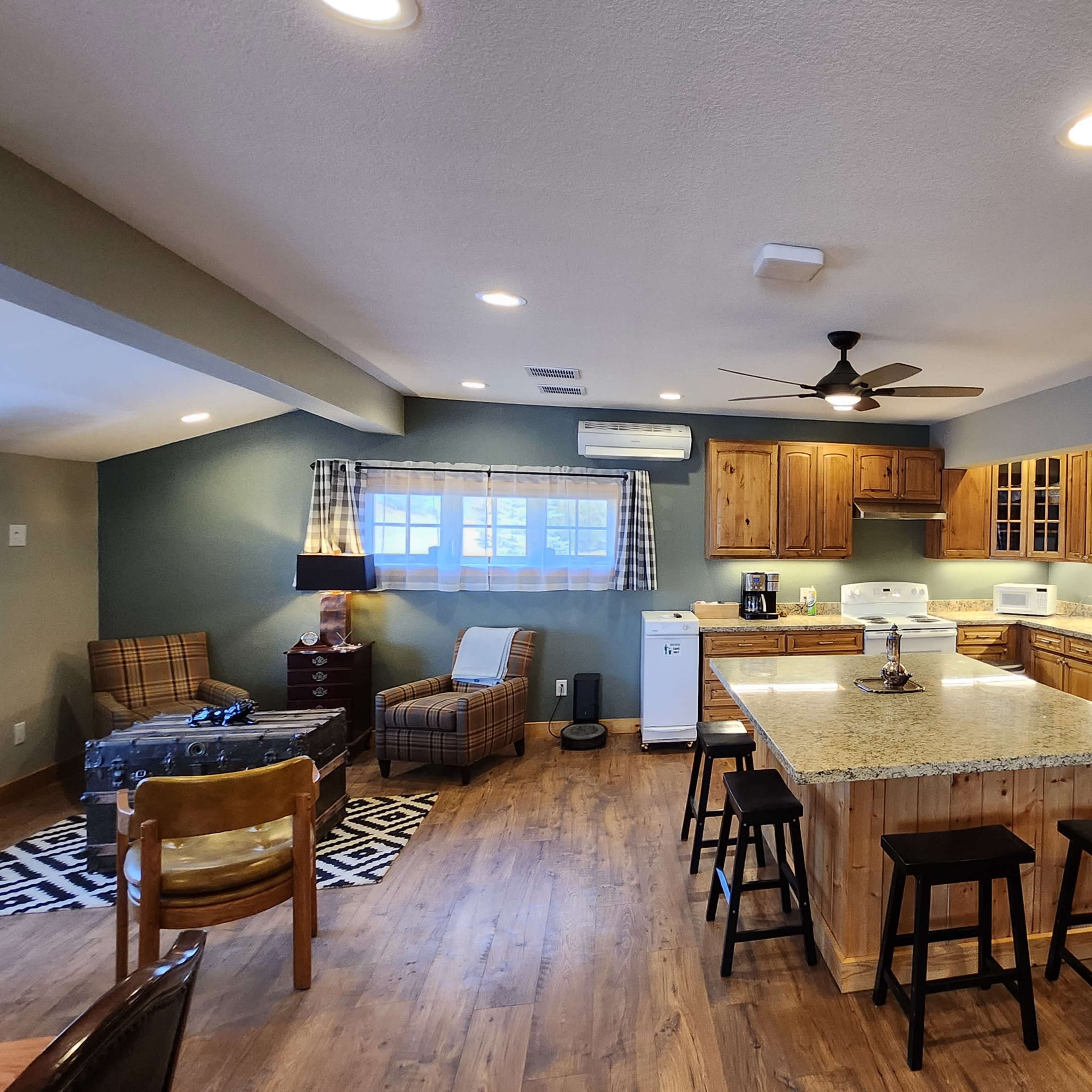 A spacious kitchen featuring wooden cabinets, a large island with a granite countertop, and modern appliances in a well-lit area.