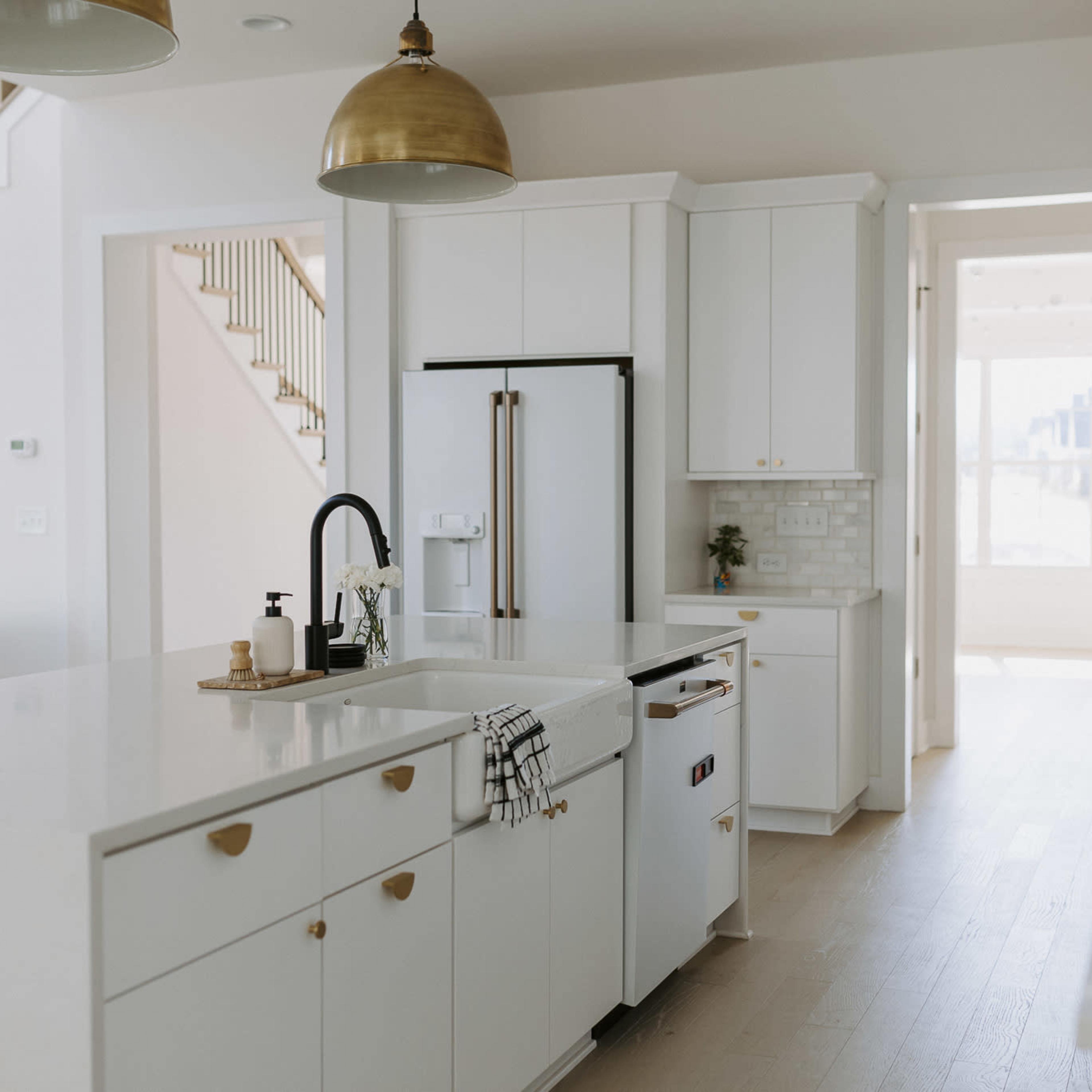 A modern kitchen features white cabinetry, a large island, and stainless steel appliances.