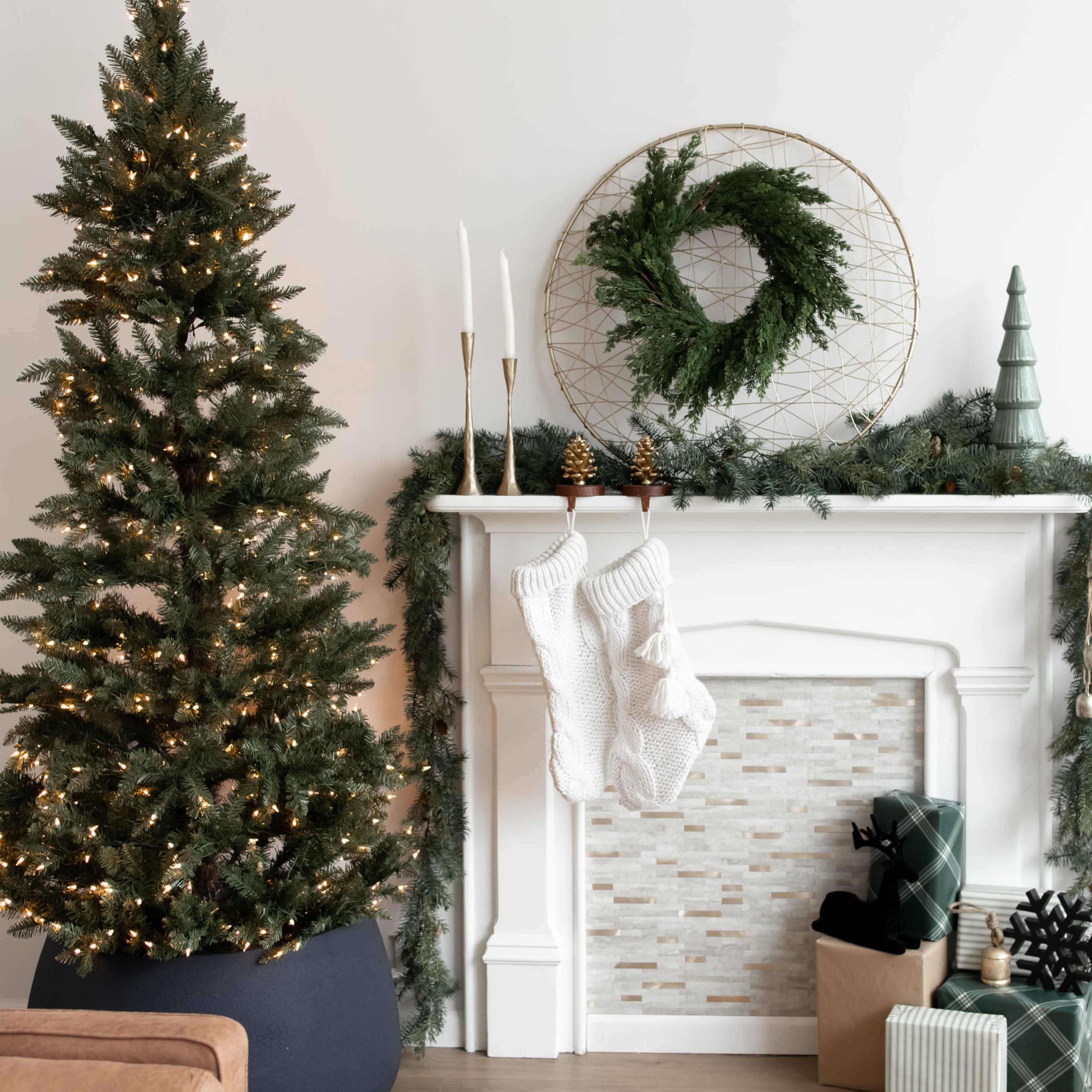 A decorated fireplace features stockings, a wreath, and a Christmas tree adorned with lights and garland.