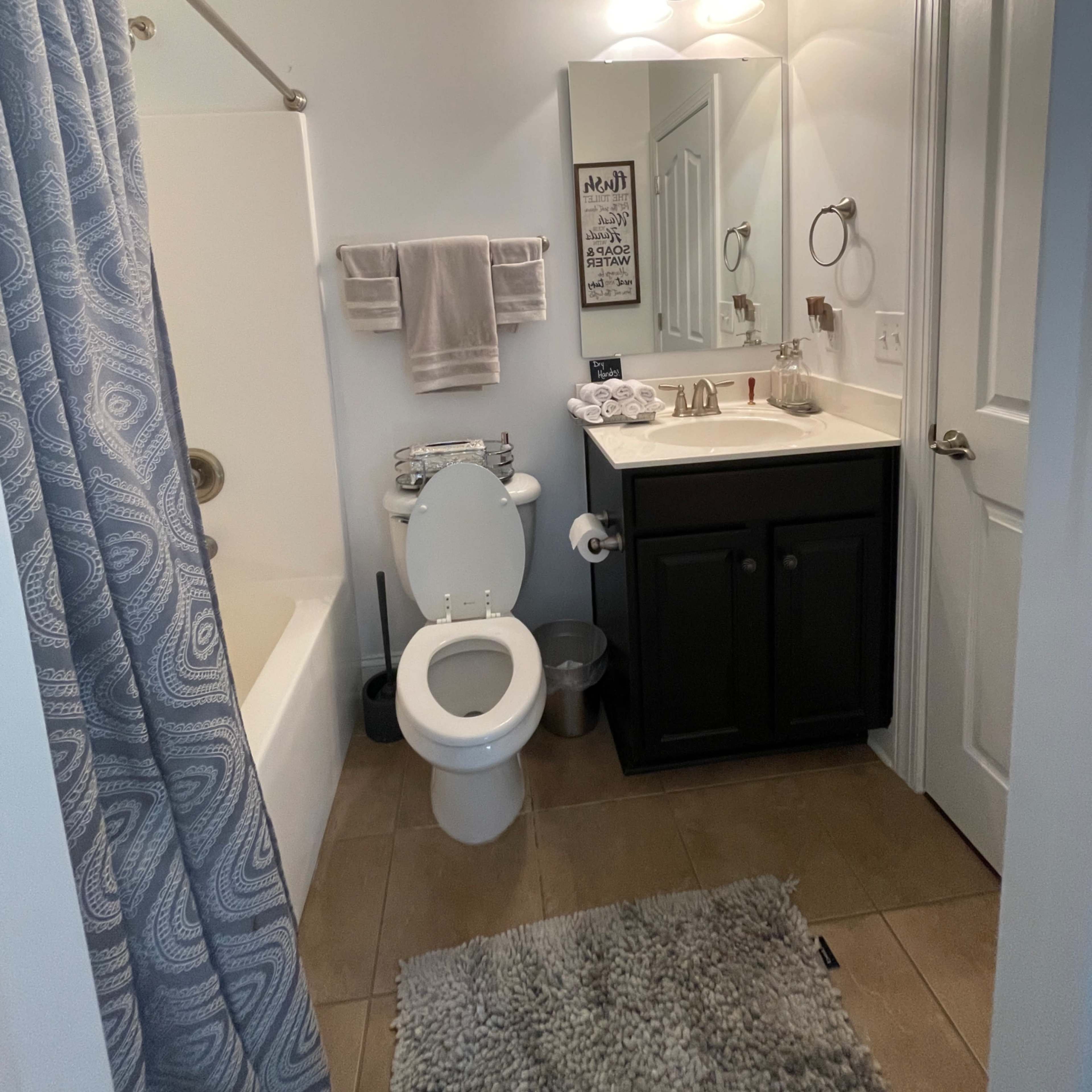 A small bathroom featuring a bathtub, toilet, sink with a cabinet, and a mirror.