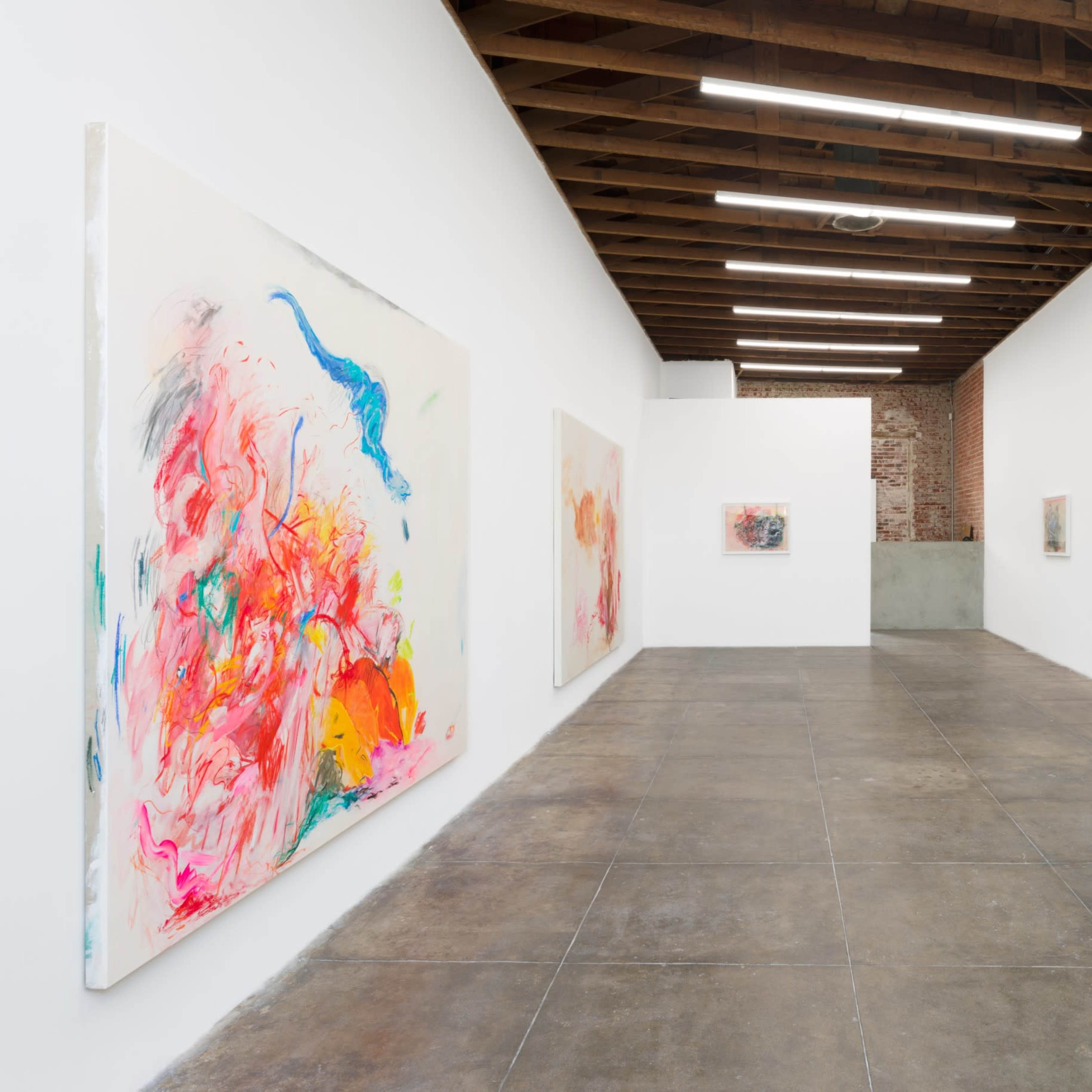 An art gallery with several large abstract paintings displayed on the white walls and a polished concrete floor.