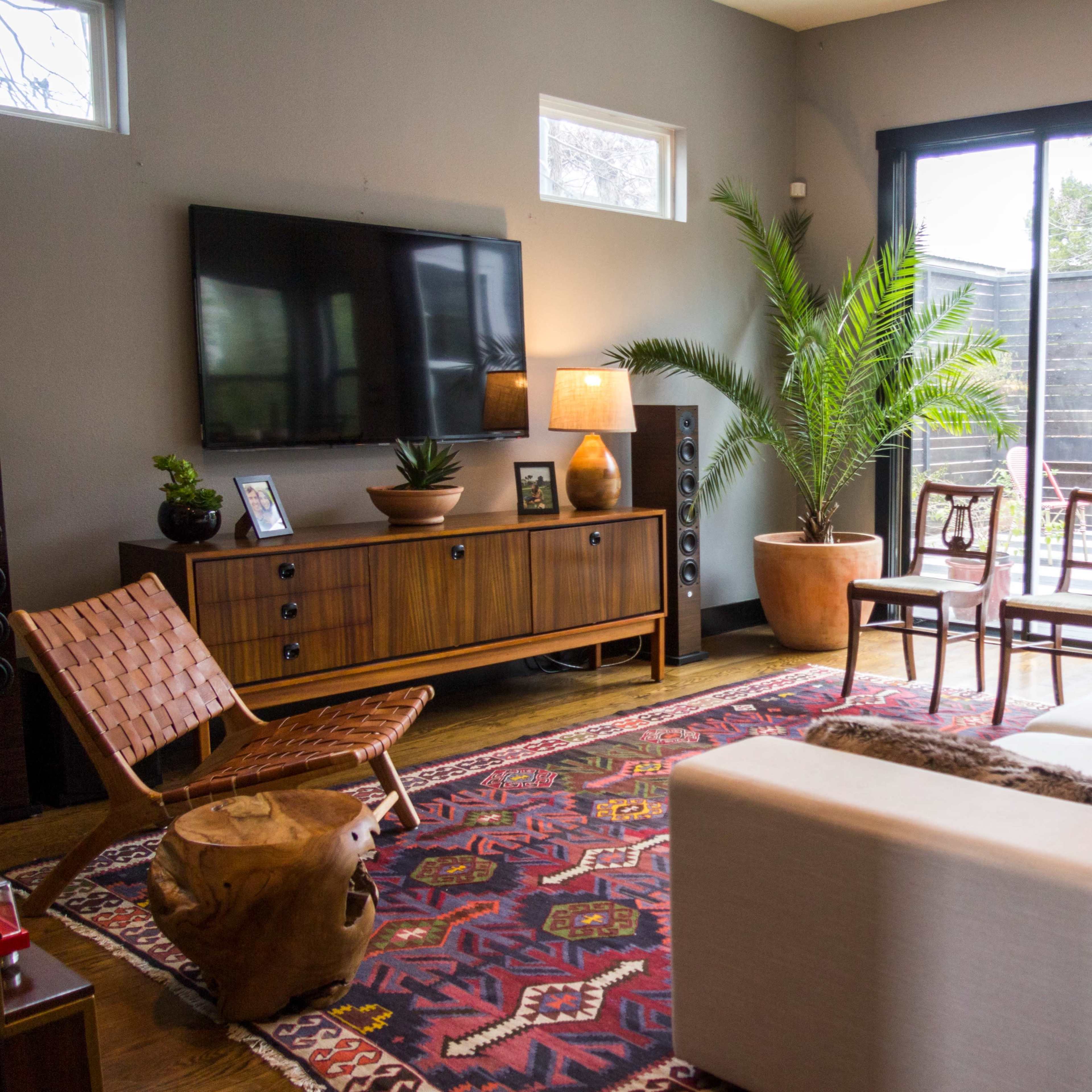 A modern living room features a sofa, a wooden side table, a television, and a sliding glass door leading to an outdoor patio.