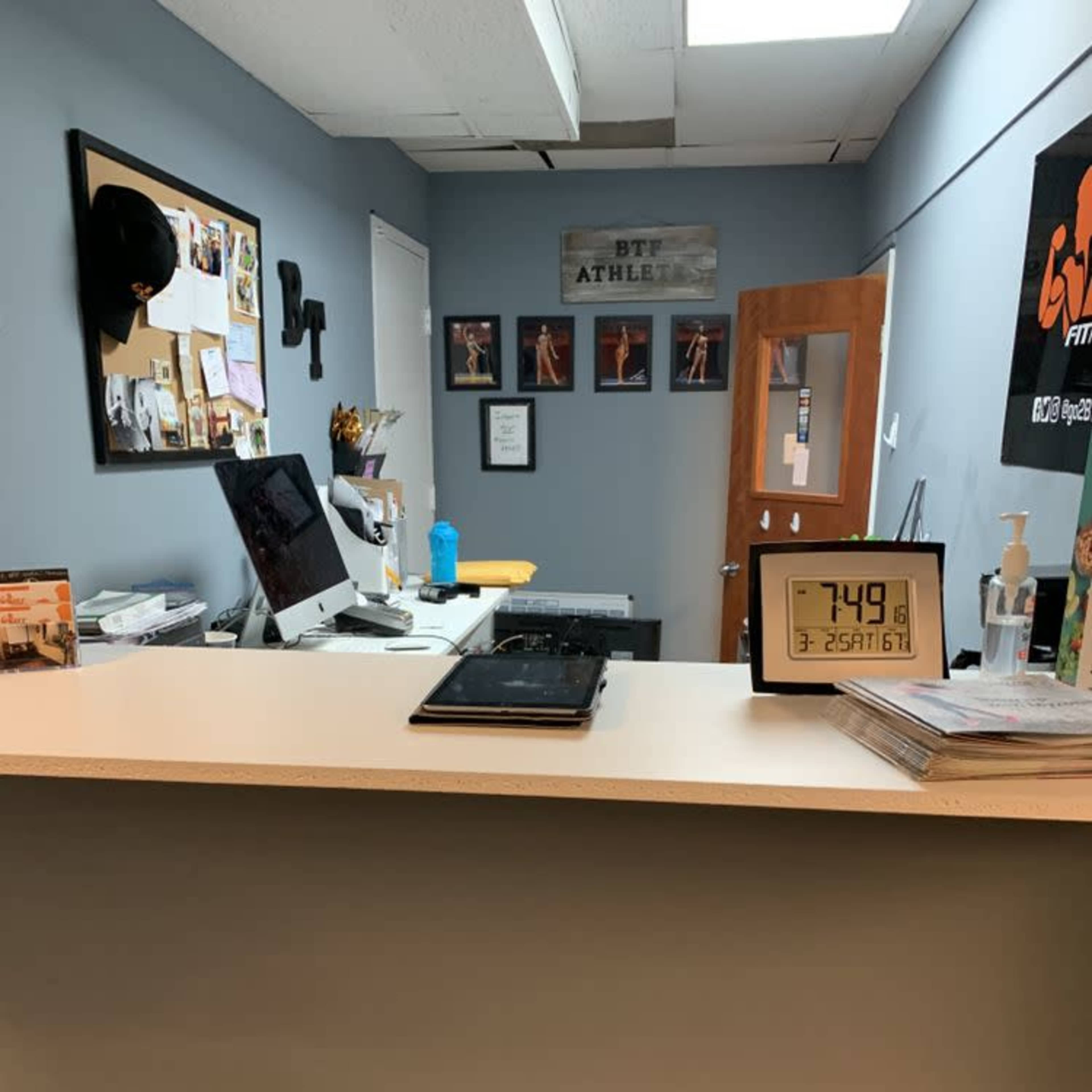 A reception area with a counter, a computer, and framed pictures on the wall.