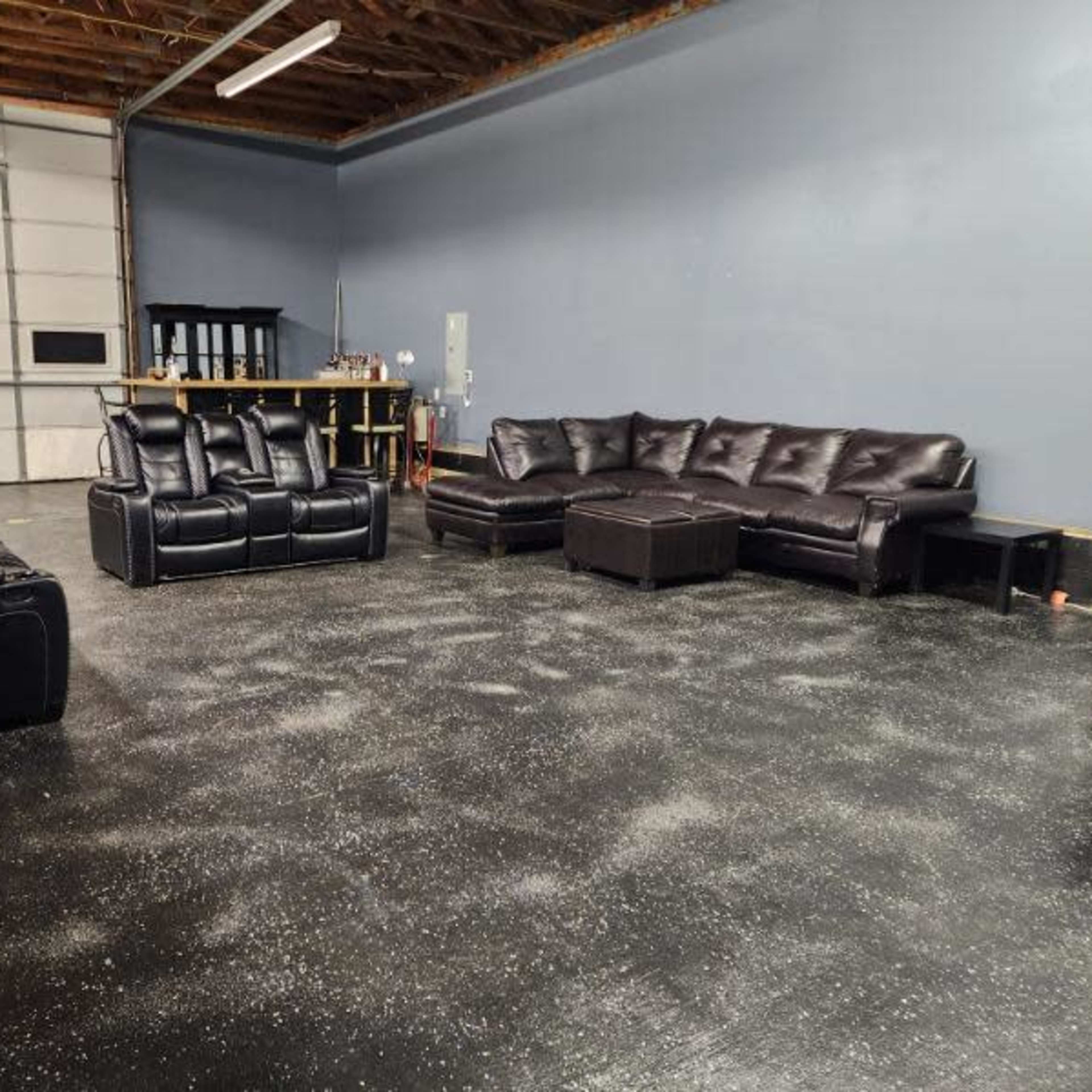 A spacious room with two sectional couches, a coffee table, and a workbench against a blue wall.