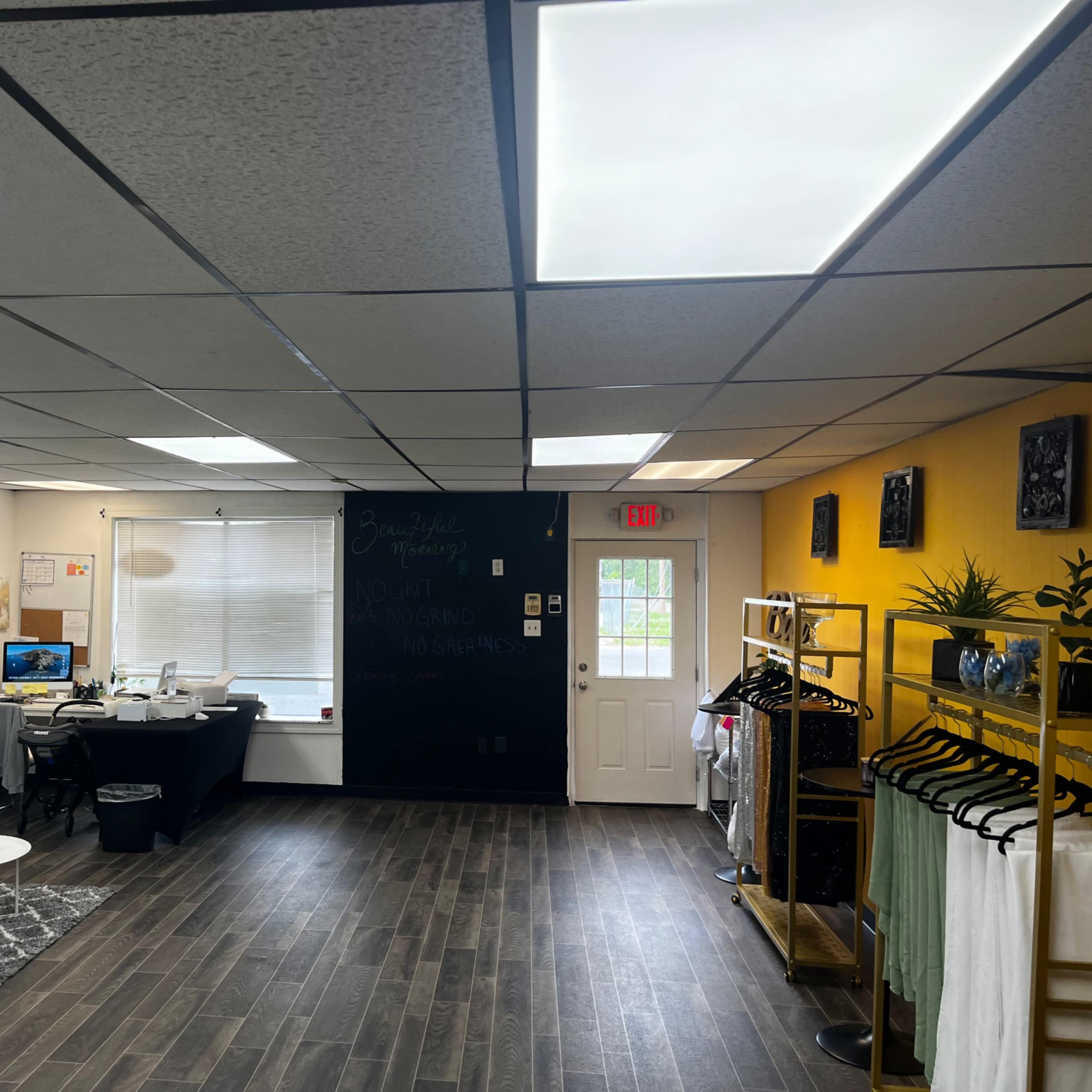 A bright, modern interior of a retail space with a white sofa, a desk with a computer, and clothing racks against the walls.