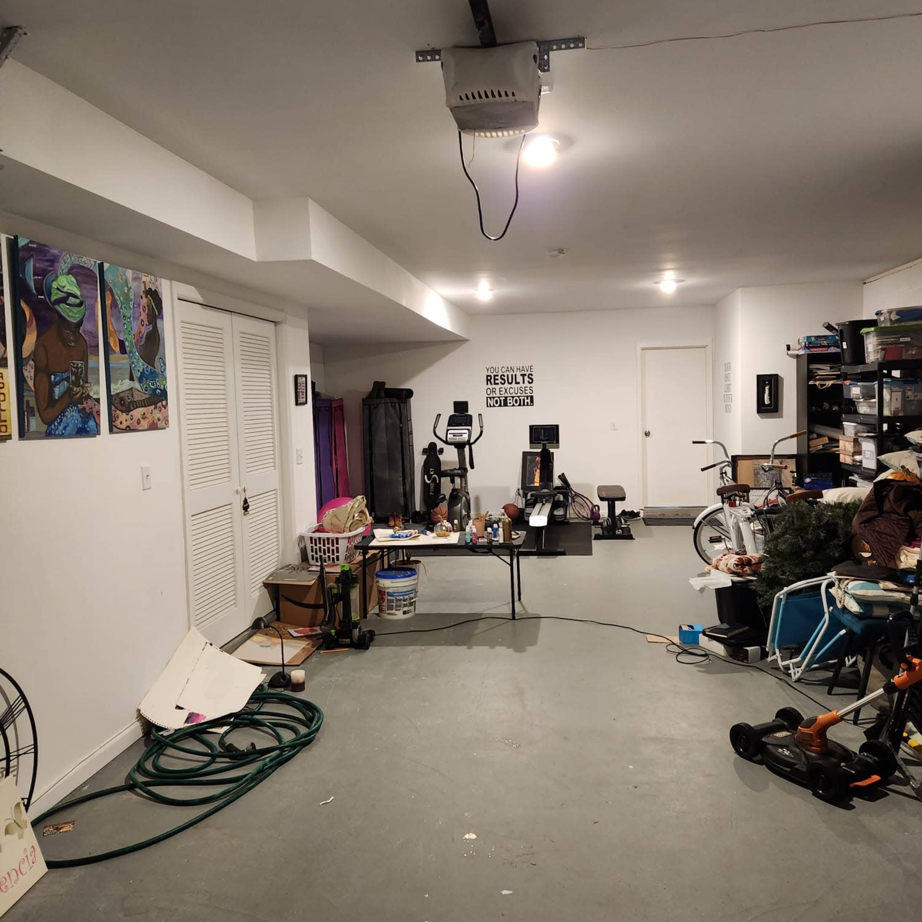 A garage filled with various items, including exercise equipment, storage bins, and art on the walls.