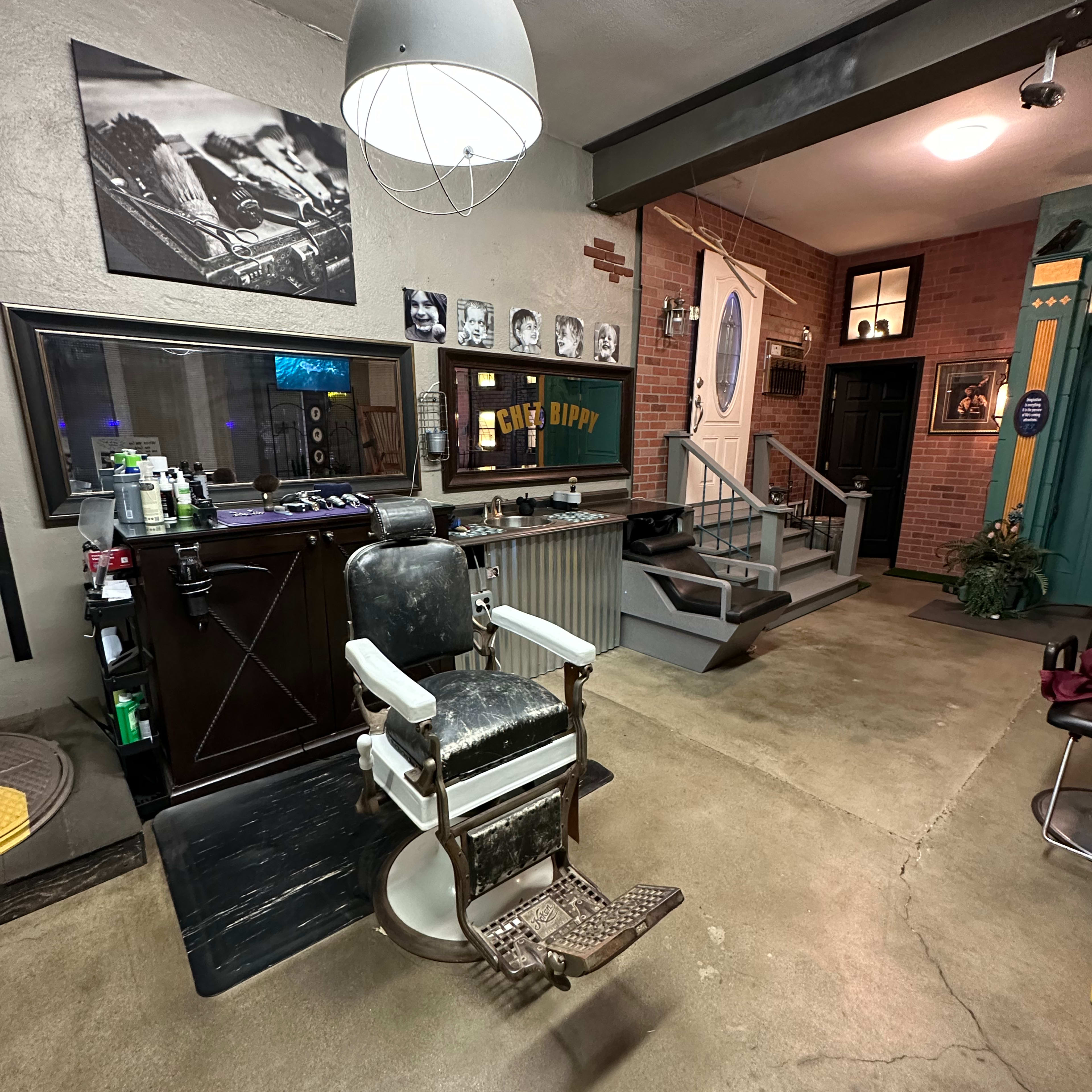 A vintage barber shop interior featuring a traditional barber chair, a large mirror, and retro décor elements like photographs and signage.