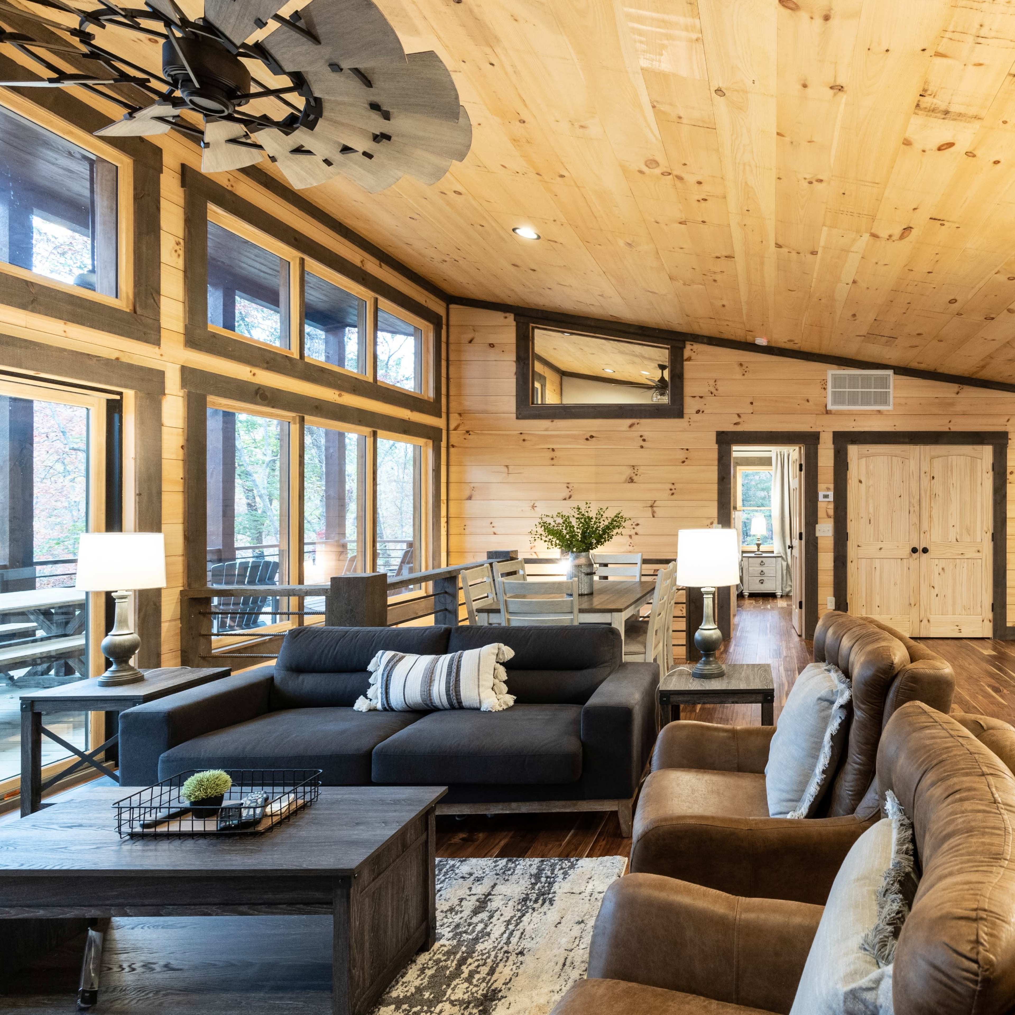 A spacious cabin-style interior with wooden walls, a modern kitchen island, and a mix of comfortable seating arrangements.