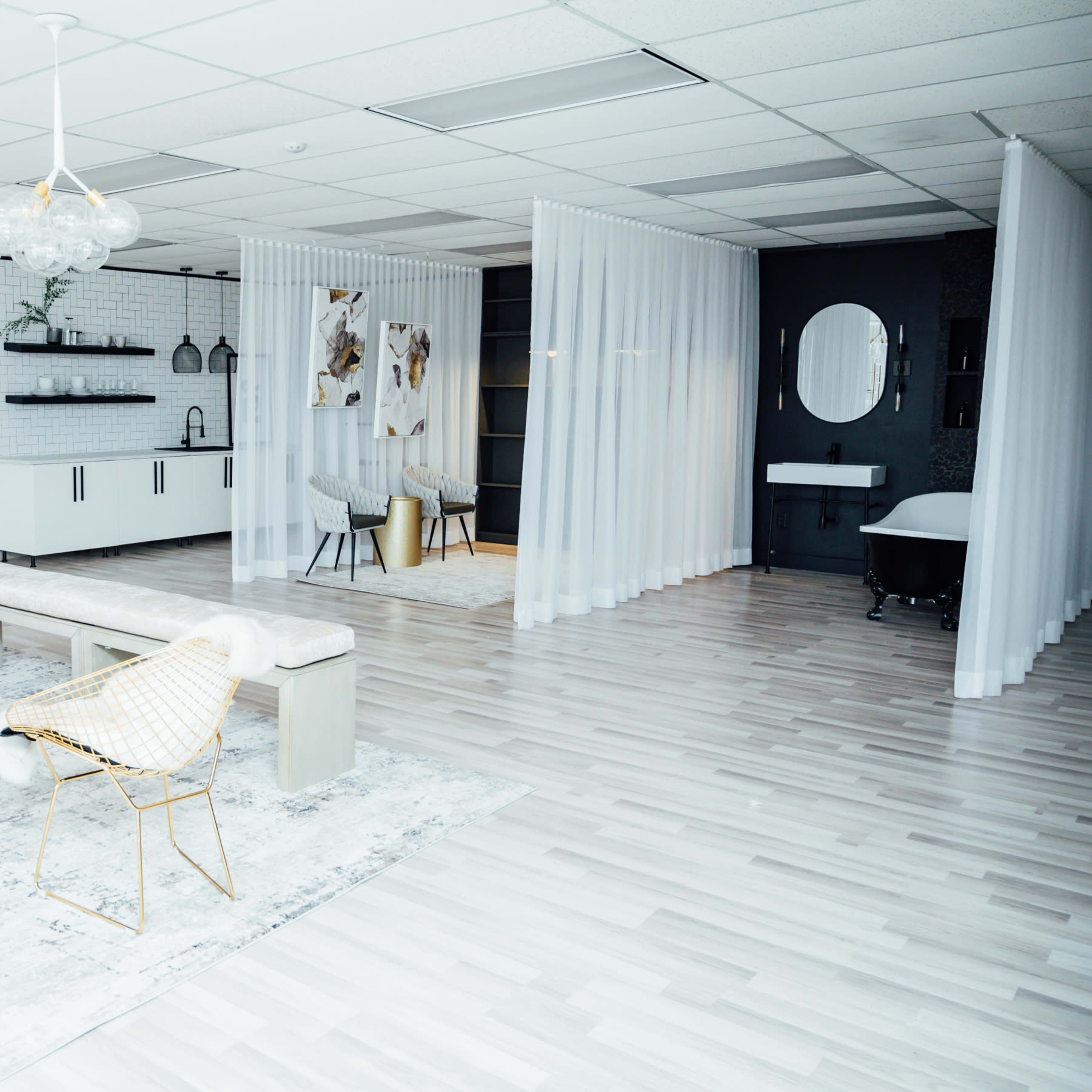 A modern interior space divided into sections with sheer curtains, featuring stylish furniture, a decorative rug, and minimalist decor elements.