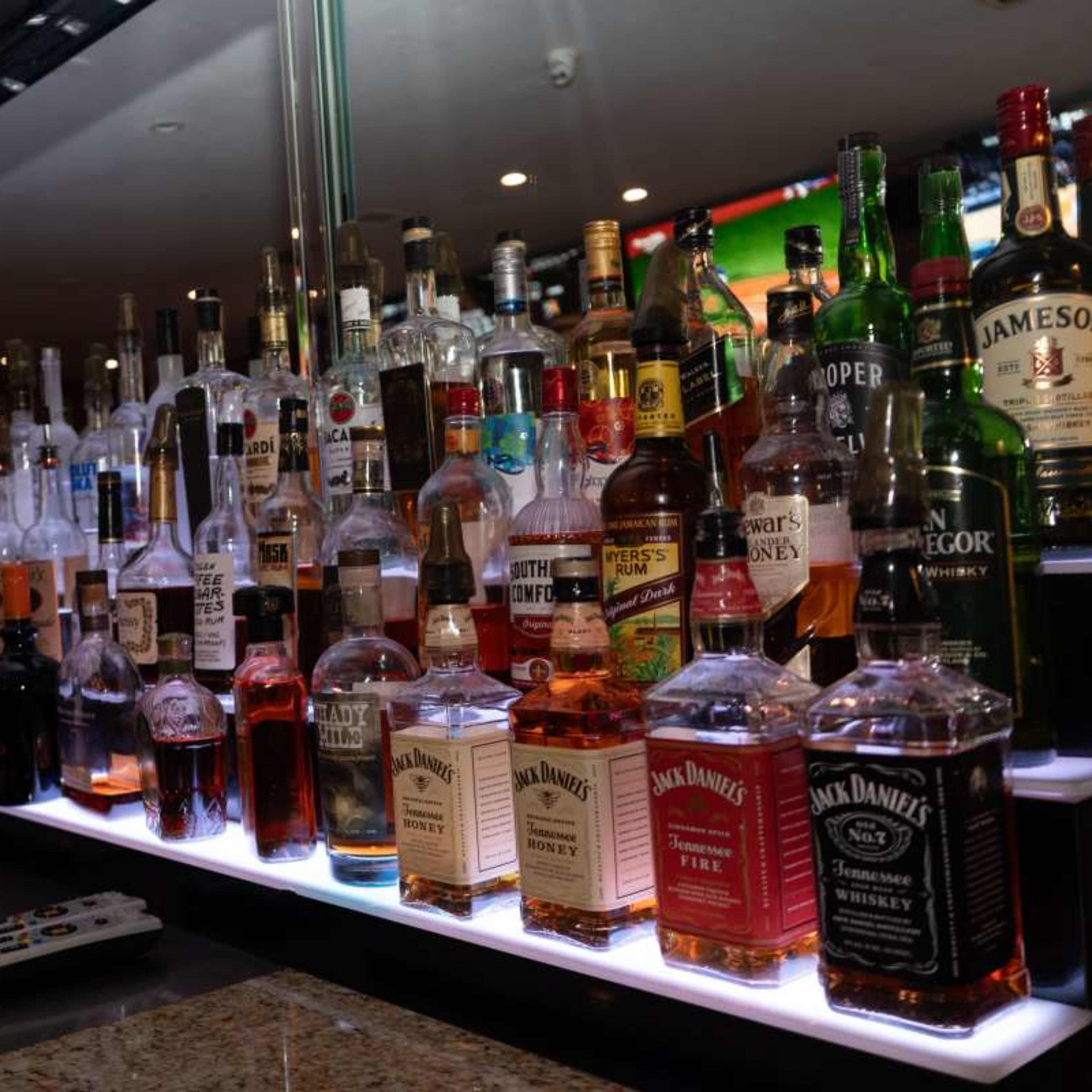 A well-stocked bar featuring a variety of liquor bottles arranged on shelves with a dimly lit background.