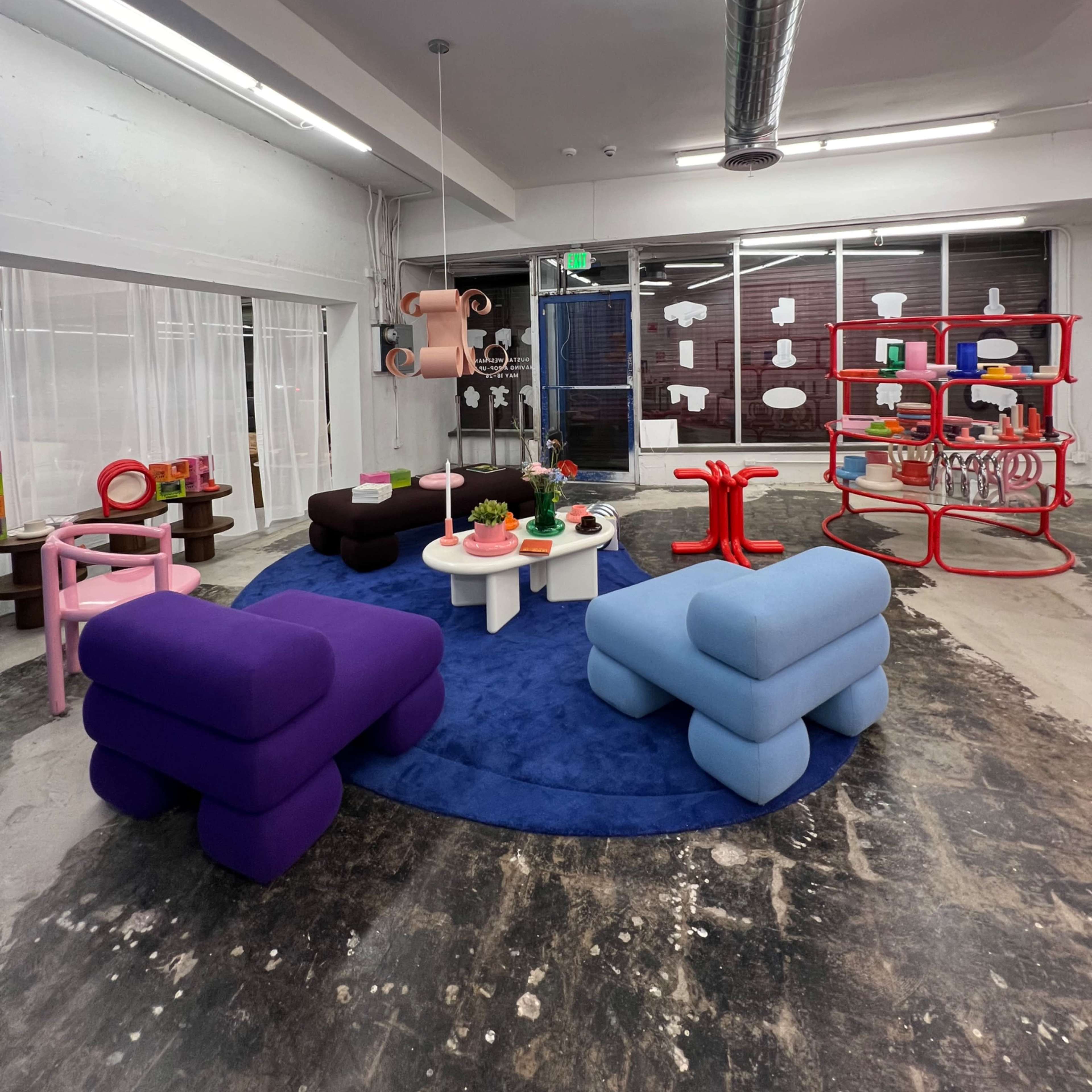 A modern interior space featuring colorful furniture items, including sofas and tables, arranged on a circular rug.