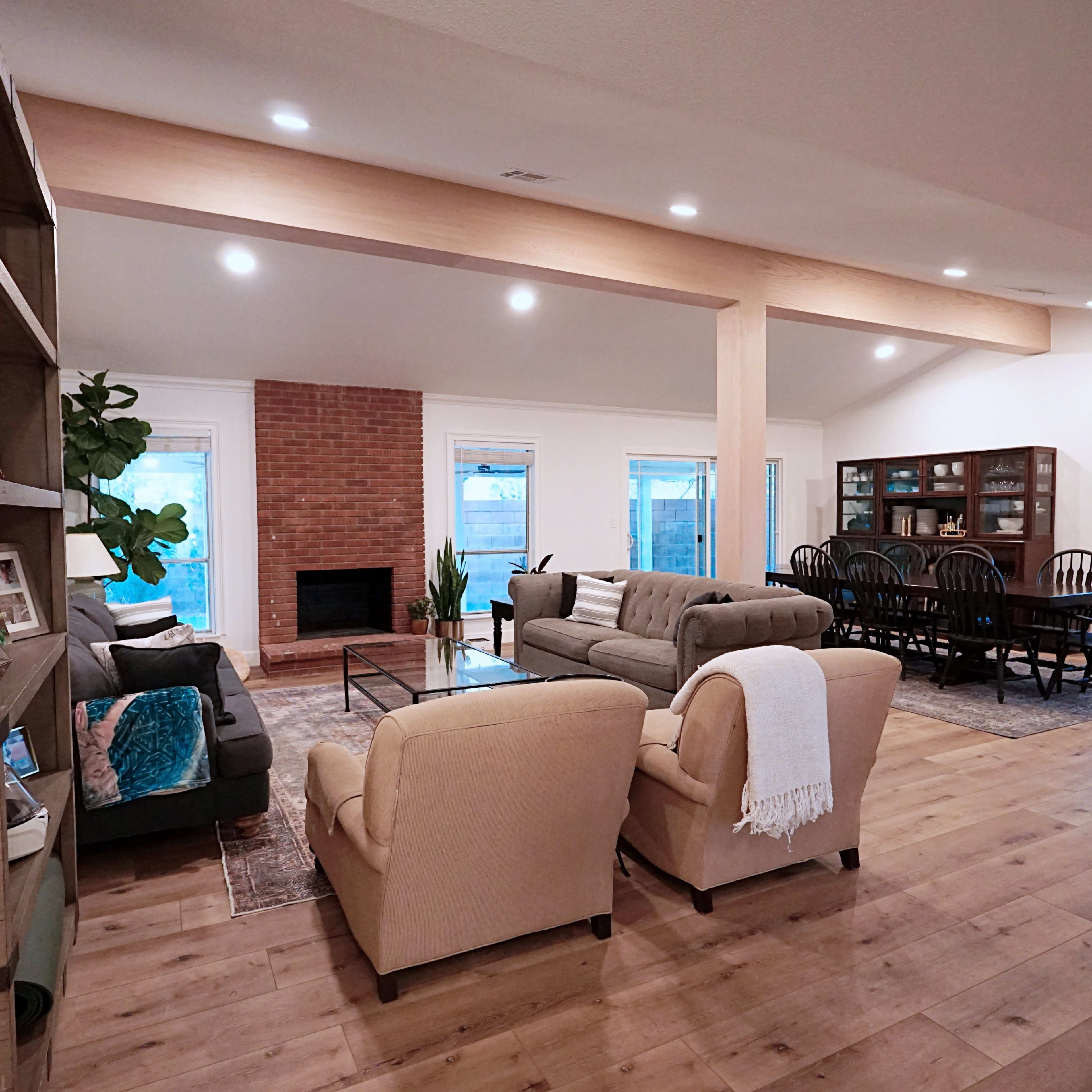 The spacious living area features a combination of seating, a brick fireplace, and a dining table with black chairs.