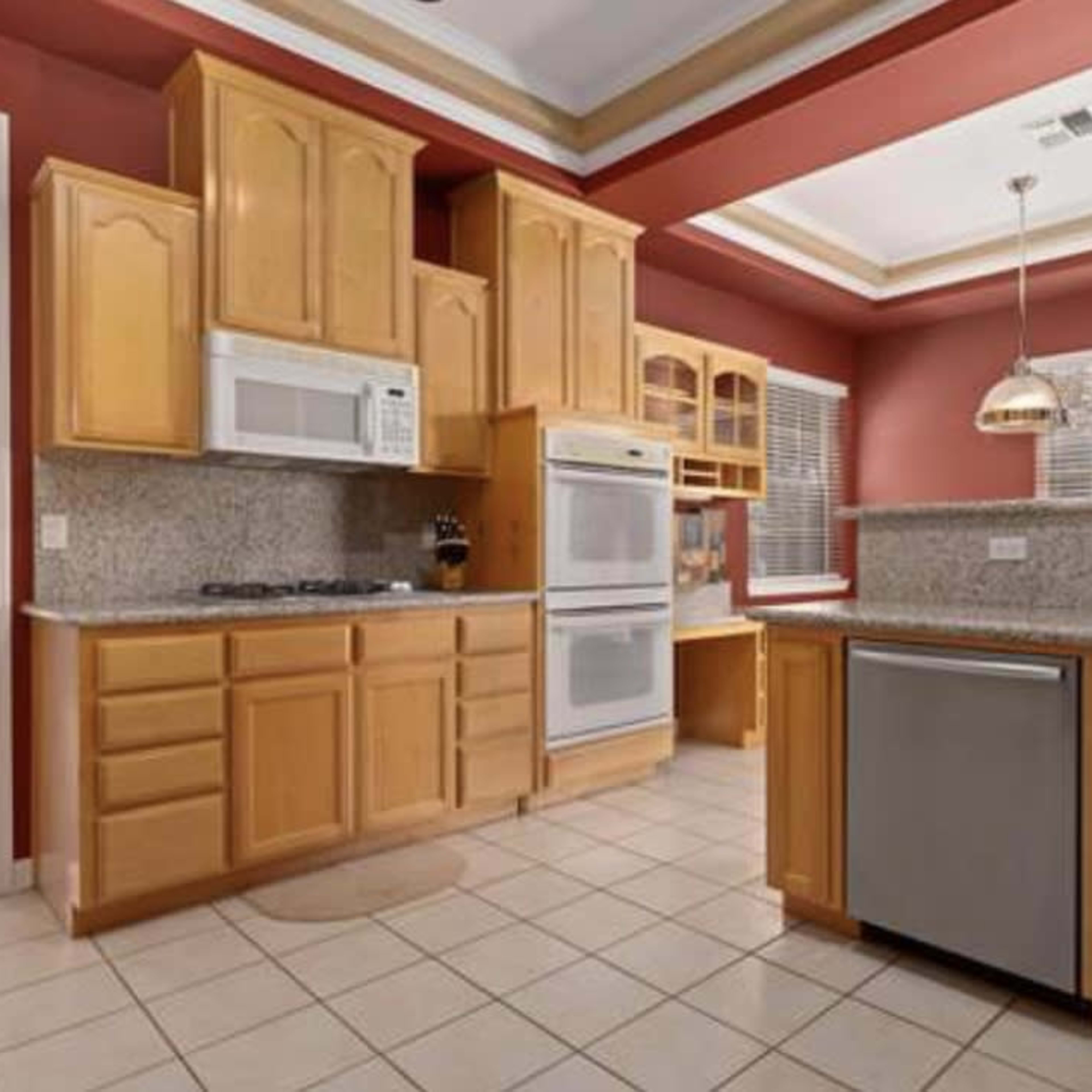 A kitchen featuring wooden cabinetry, granite countertops, and appliances including a microwave and a refrigerator.