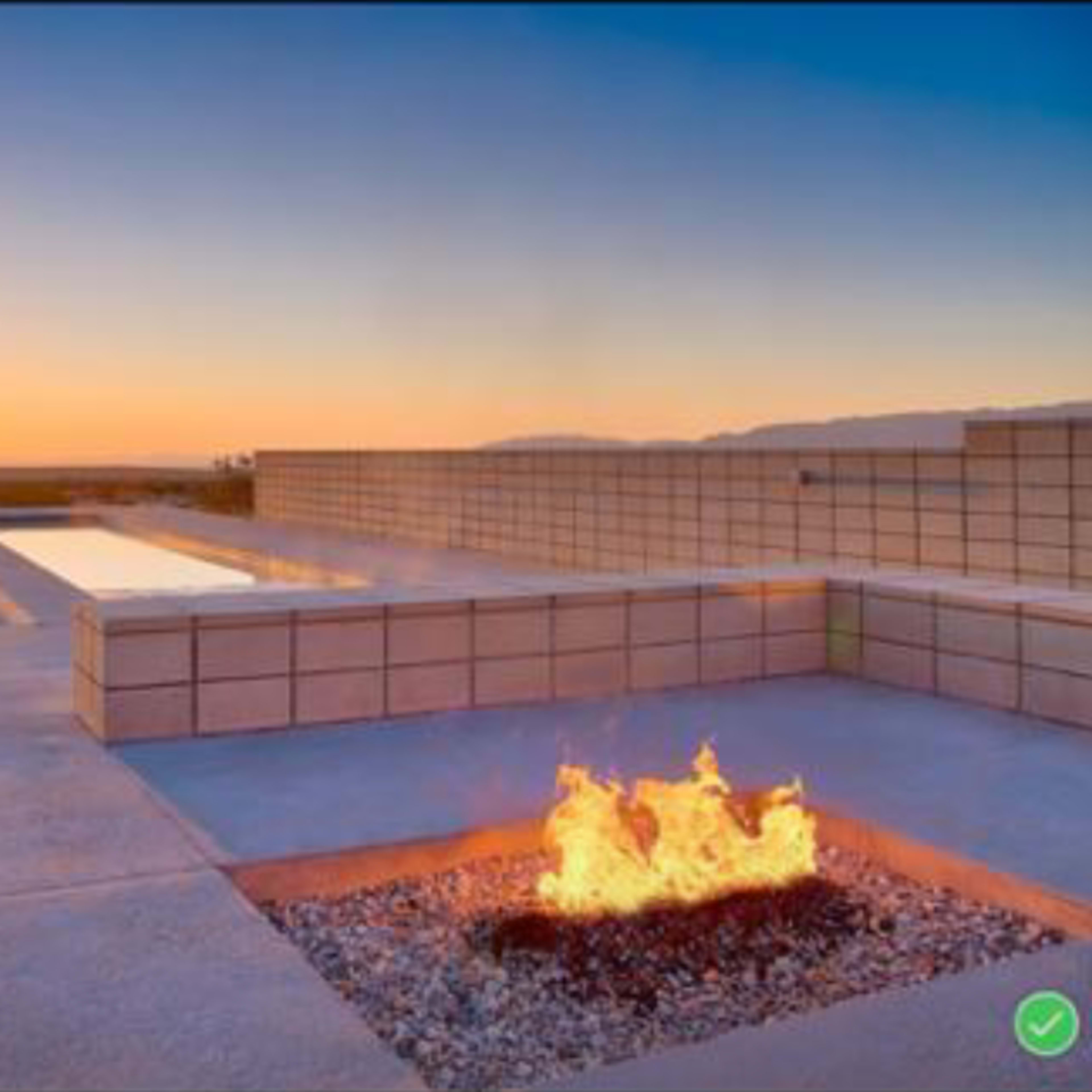 A modern outdoor space with a fire pit, a reflecting pool, and a sunset in the background.