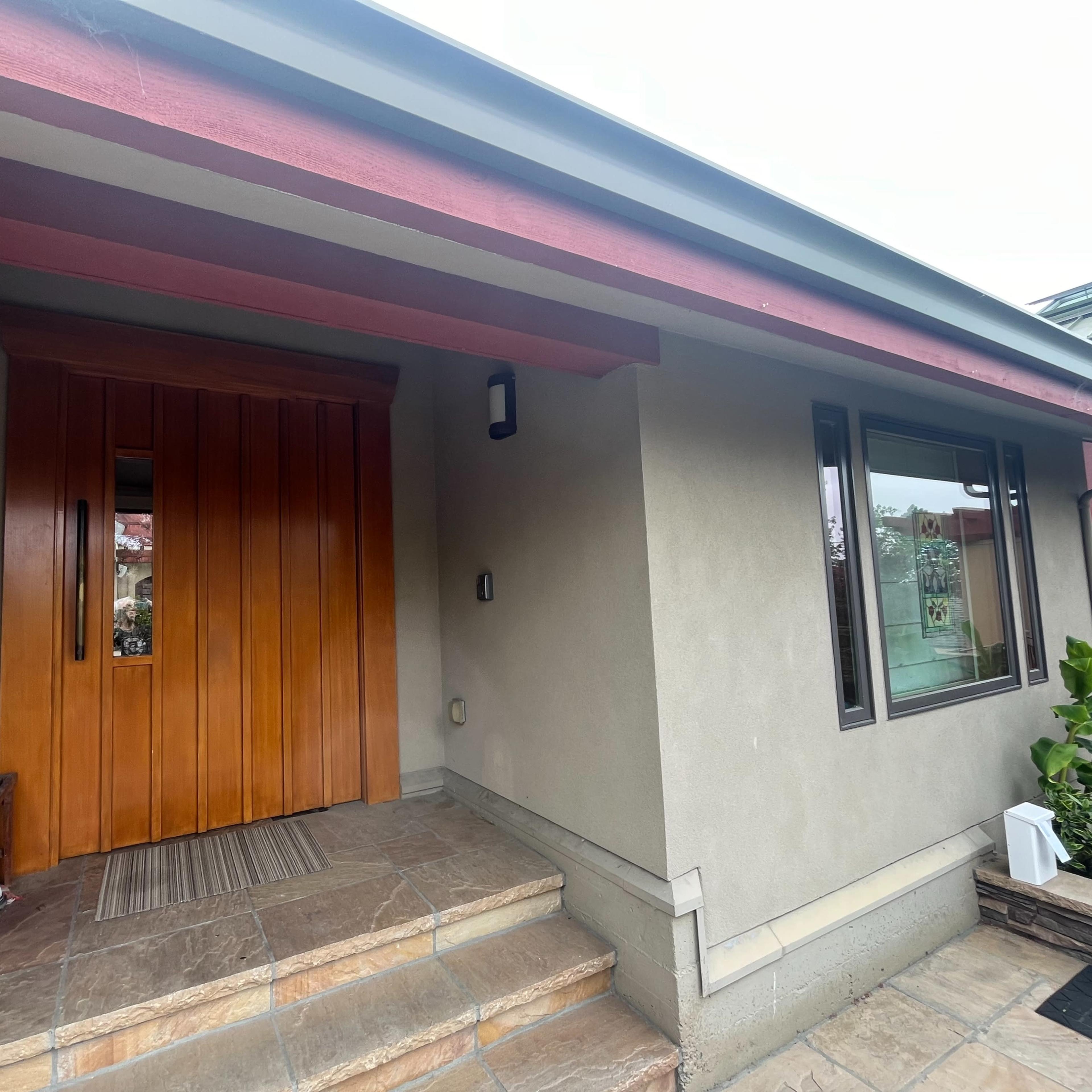 A house entrance with wooden double doors, a stone pathway, and a bench beside the door.