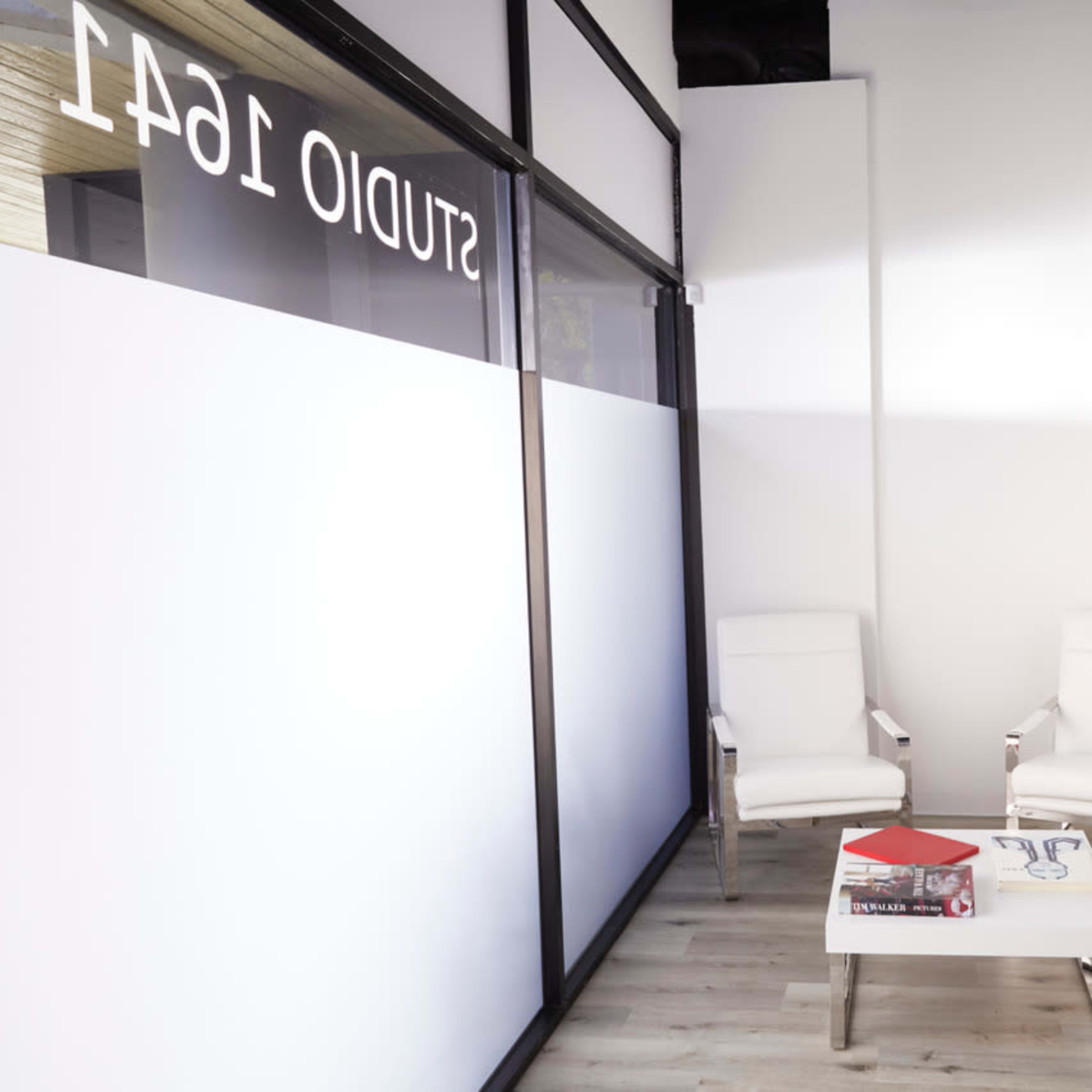 A minimalistic interior with two white chairs facing a small coffee table in a well-lit corner.