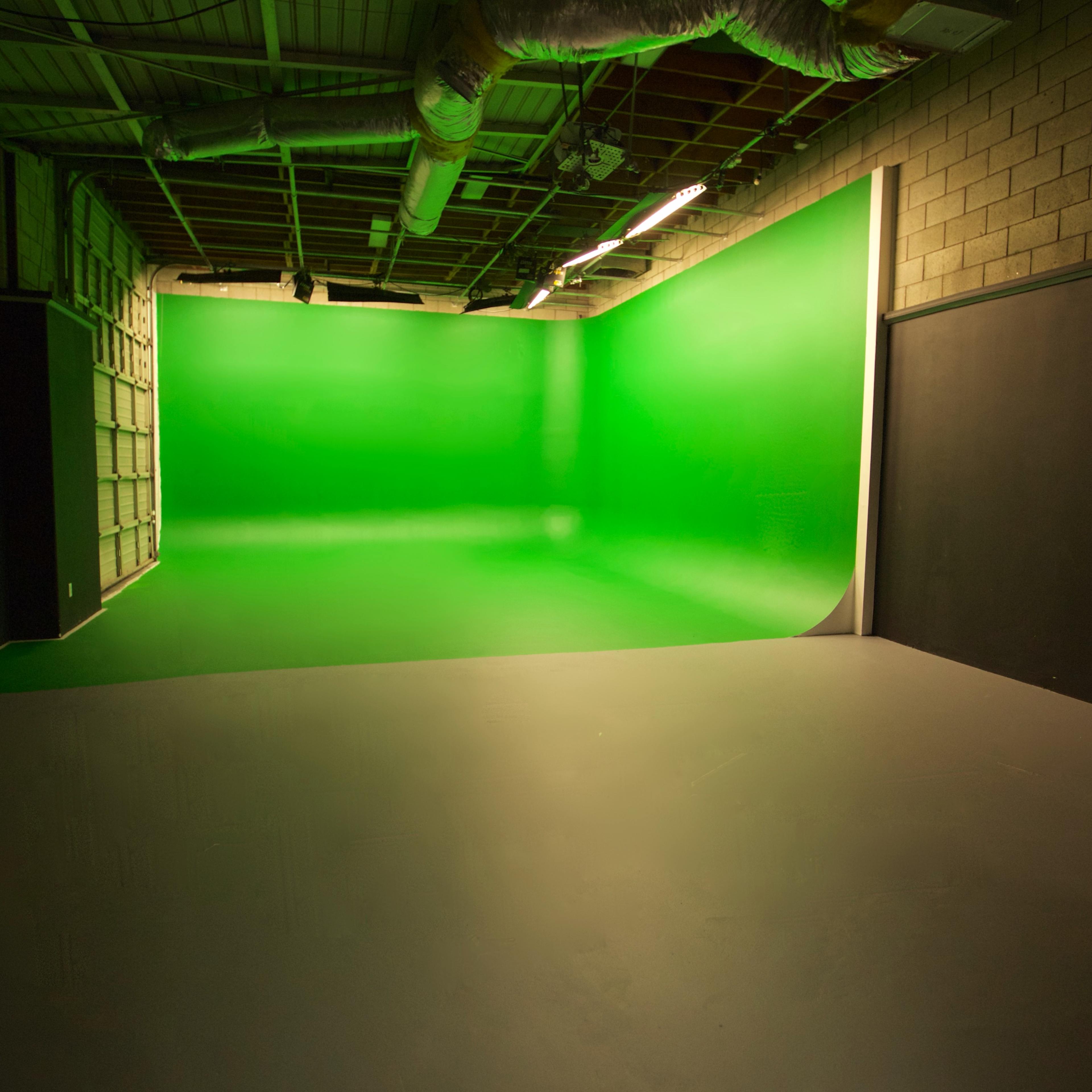 A green screen studio with a smooth gray floor and textured walls.