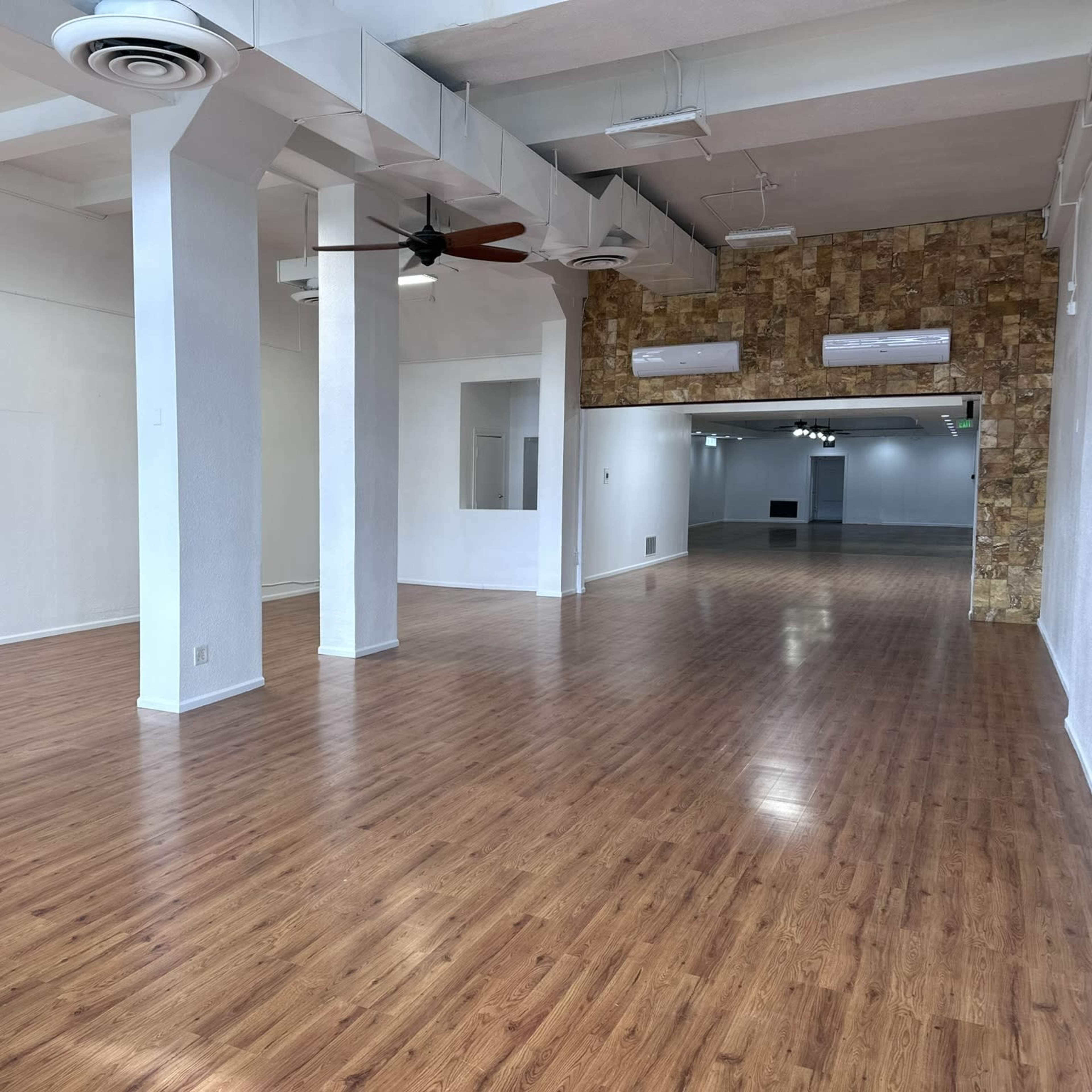 A spacious interior room with wooden flooring, white walls, and decorative stone accents.