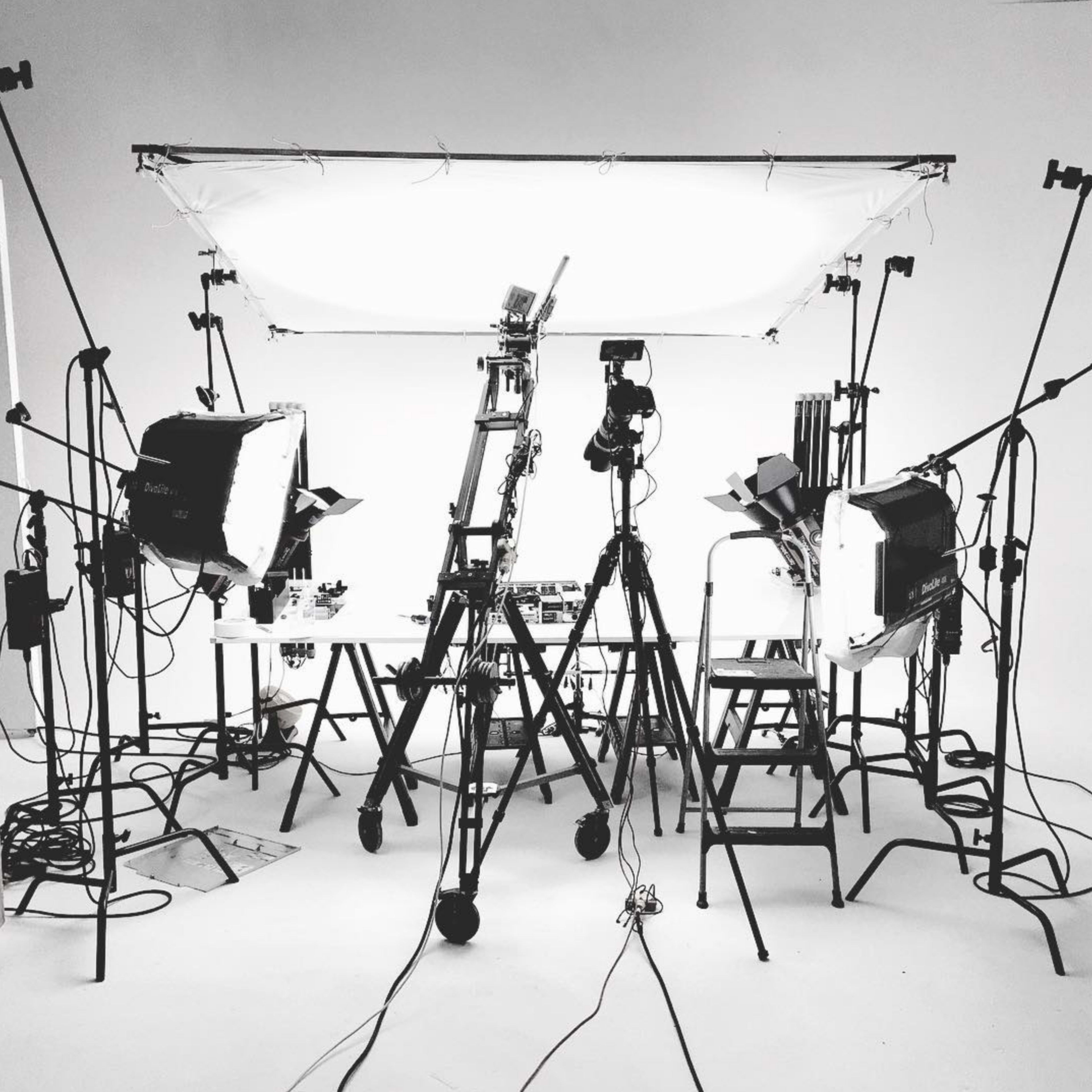 A photography studio setup with multiple lights, tripods, and a white backdrop.