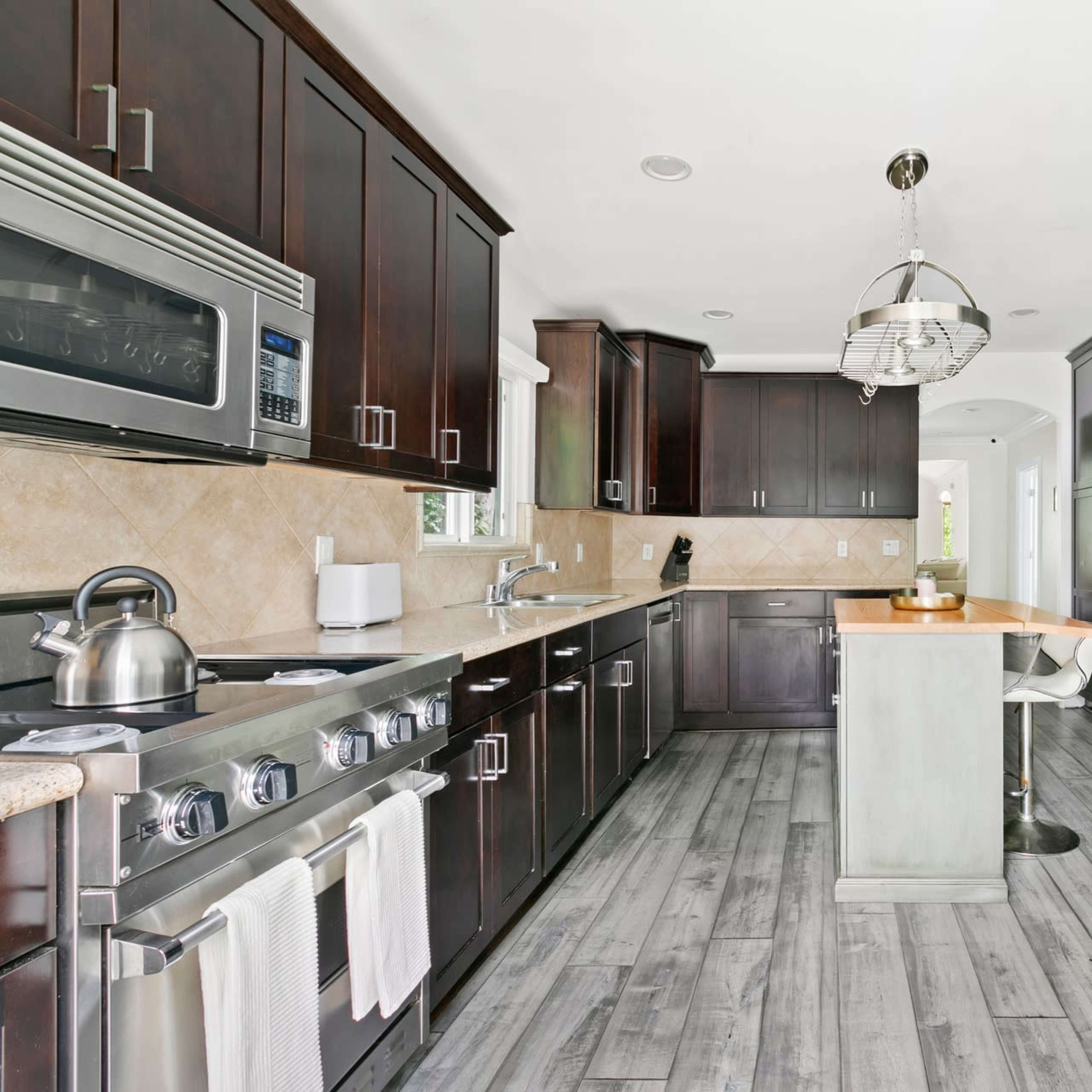 A modern kitchen features dark cabinetry, stainless steel appliances, and a central island with a light-colored countertop.